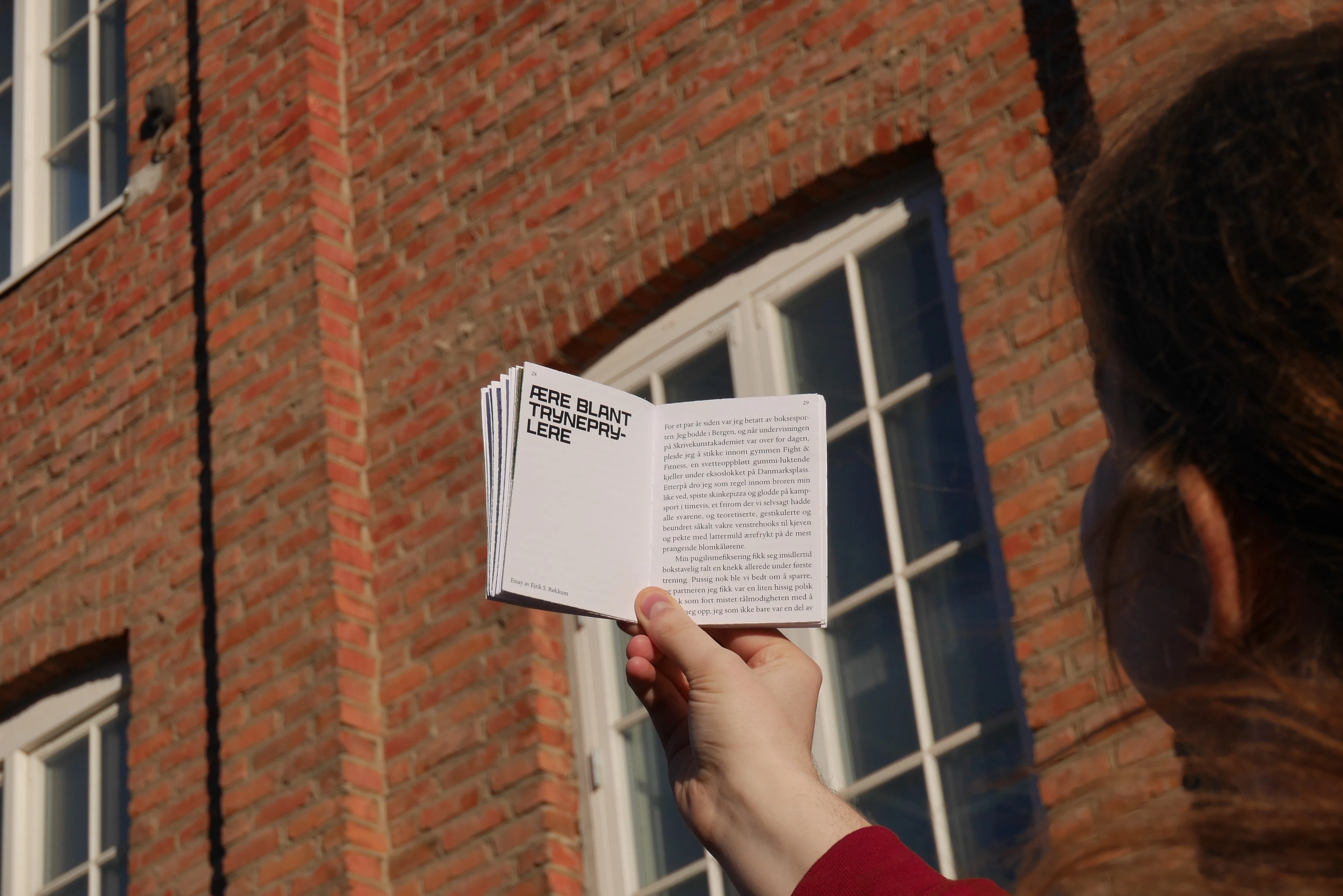 Lommeboka Litteraturtidsskrift åpen og holdt opp mot i luften