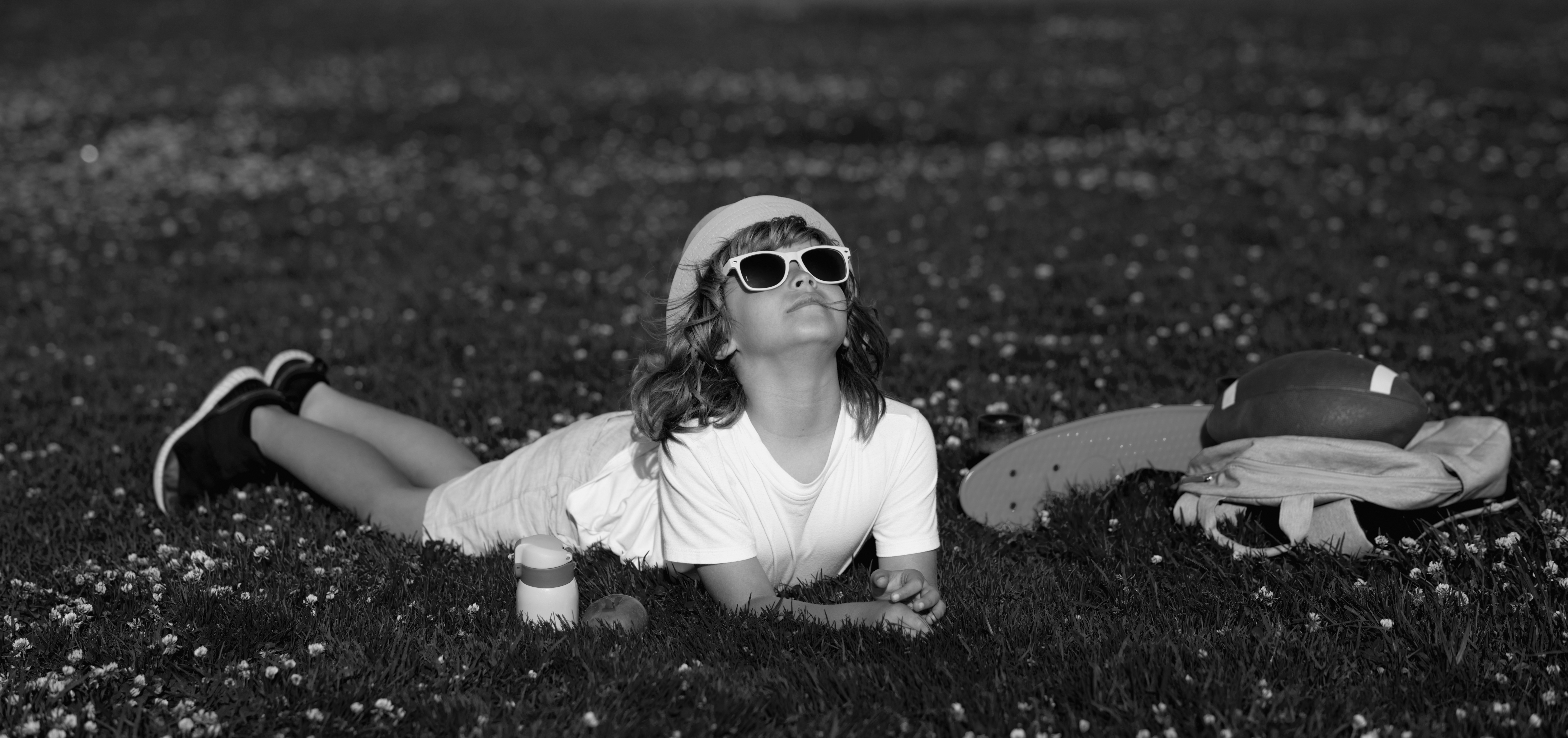 Black and white photo of a person with sunglasses lying in a grassy field.