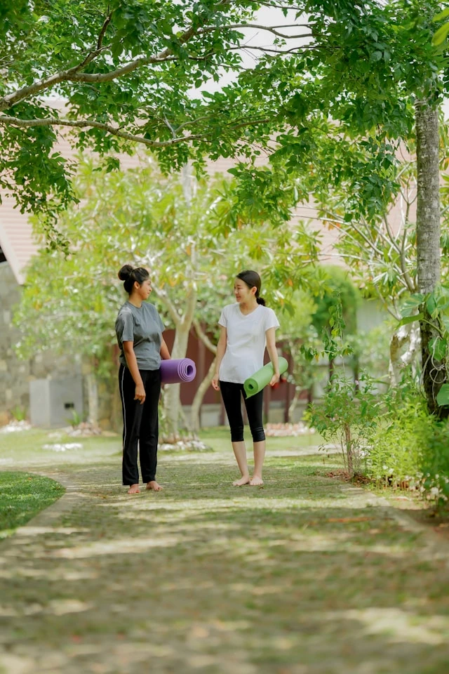 Two women standing outdoors in a green garden setting
