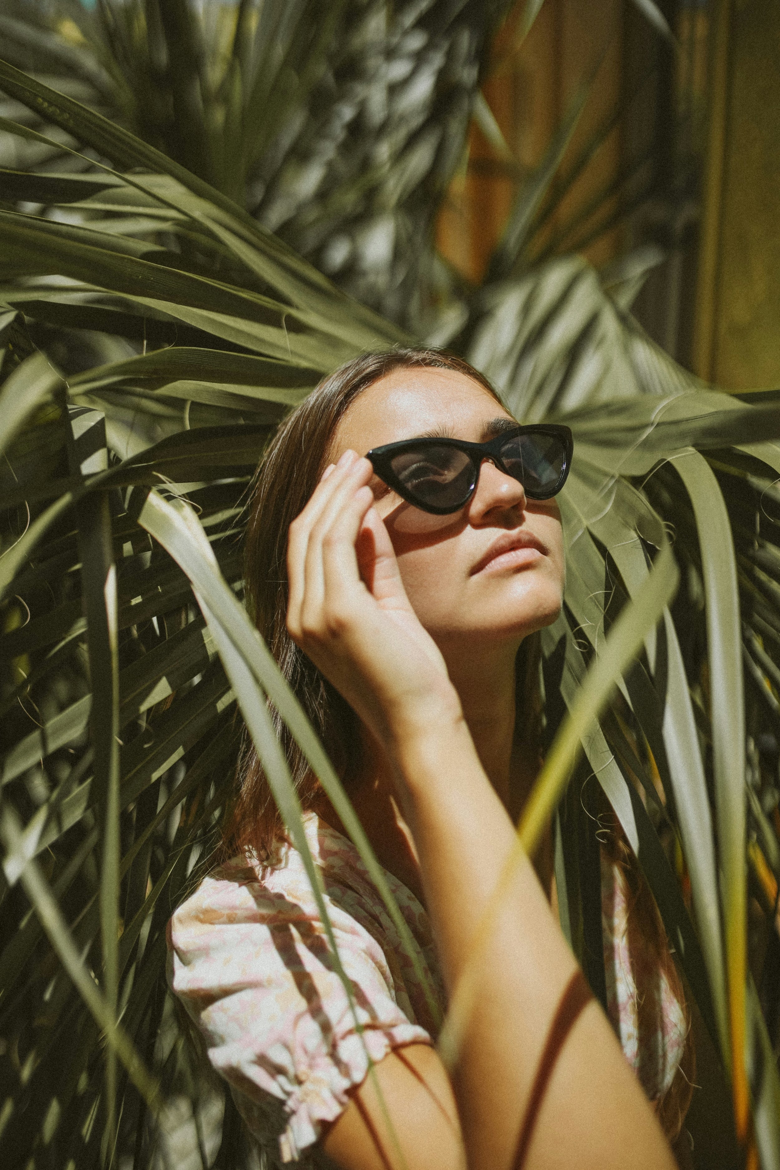 A girl in cat-eye glasses against a green background.