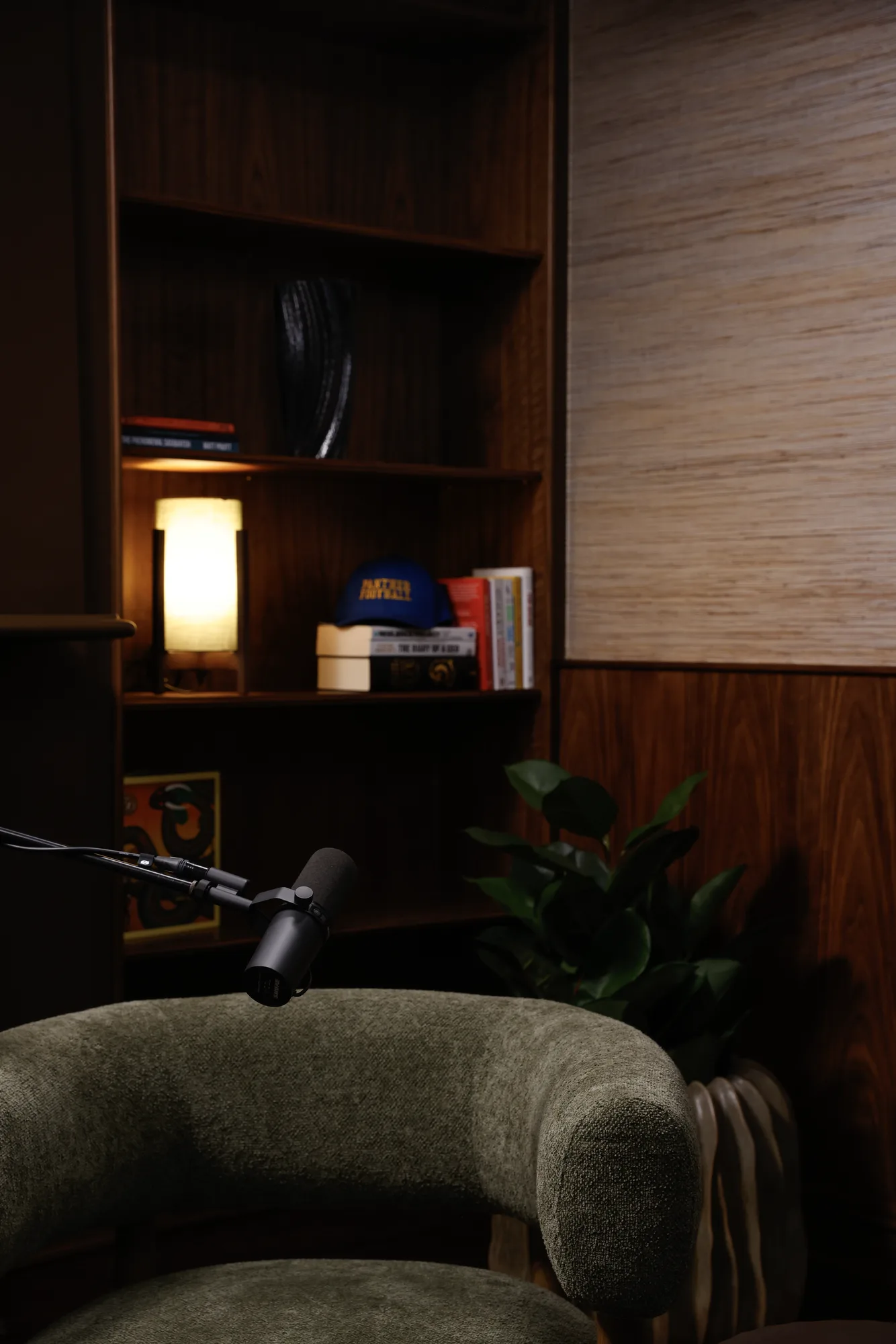 A microphone beside a lamp-lit bookshelf and green armchair on the ASPEN set
