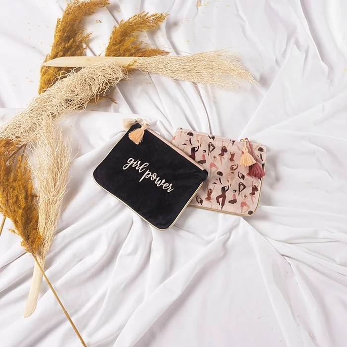 Deux pochette de la boutique Merci Chéri, posées sur un tissu blanc avec des fleurs séchées.
