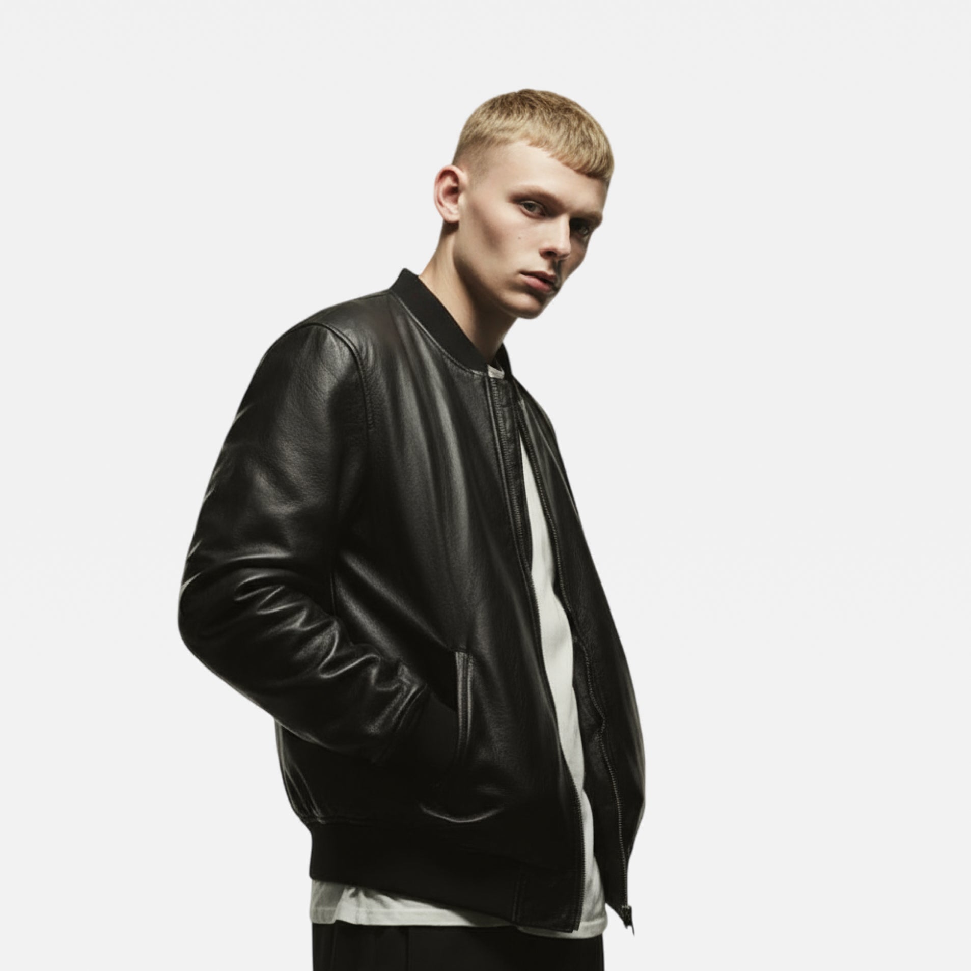 Model wearing a fitted black leather jacket with front zip closure