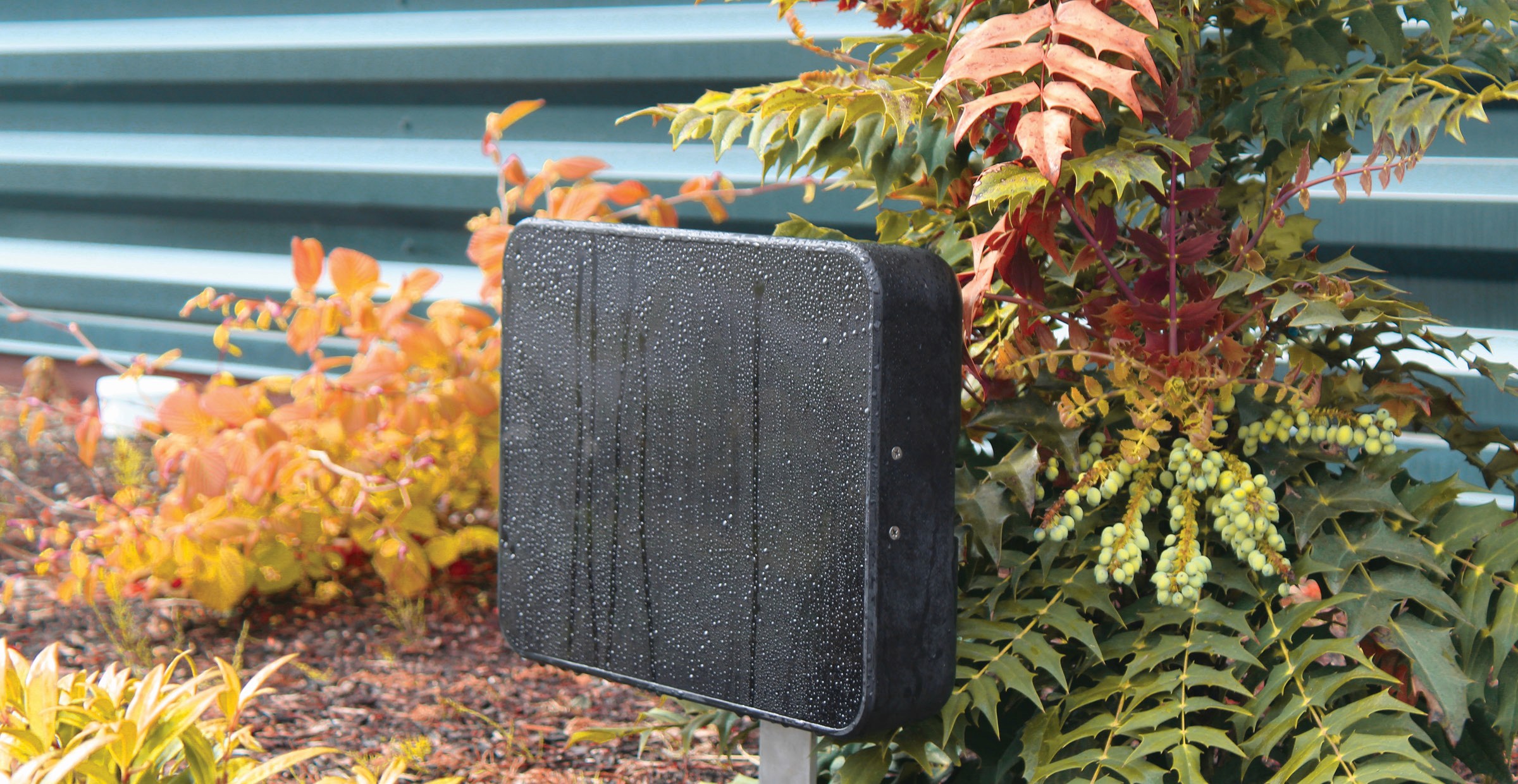 Black, wet, rectangular post with plants.