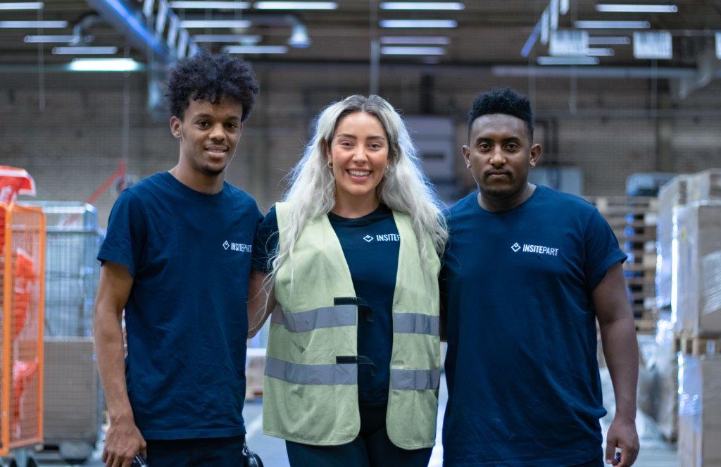 Two colleagues smiling while working together on a laptop.