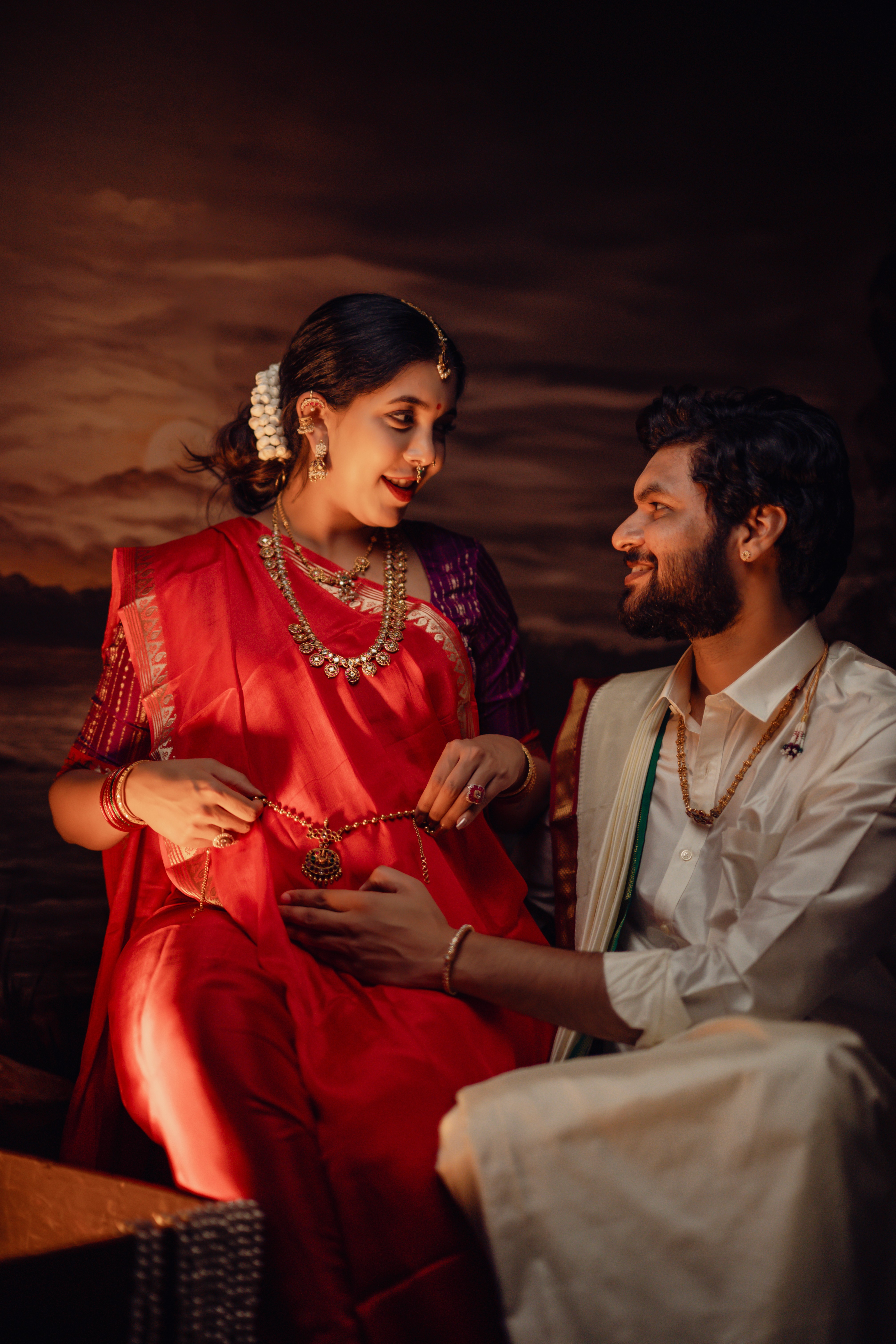 Maternity photoshoot of couple in traditional attire against a floral backdrop, captured by Wow Makers in Hyderabad, India.