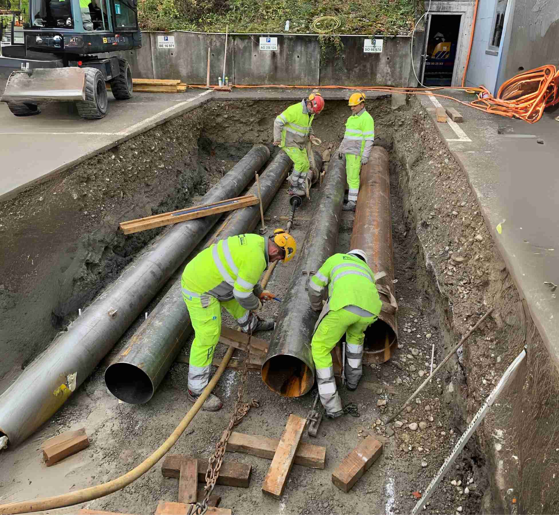 Strub Bau AG crew installing large underground utility pipes on a construction site – professional pipeline installation and civil engineering services.