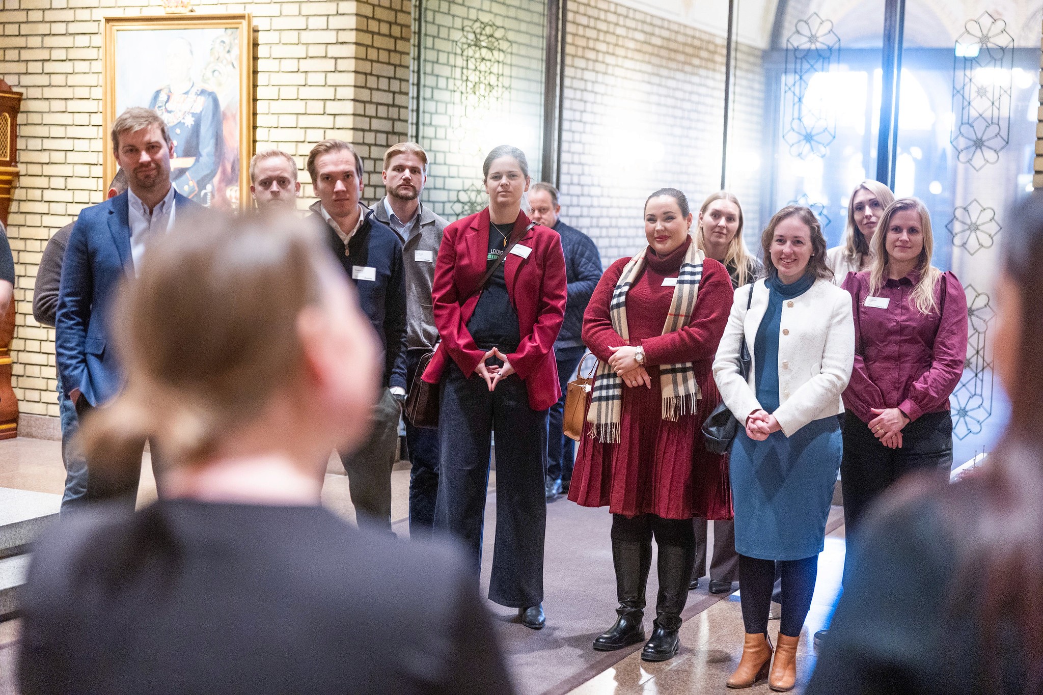 A group of people mingling at an event, with one man looking upwards, appearing deep in thought.