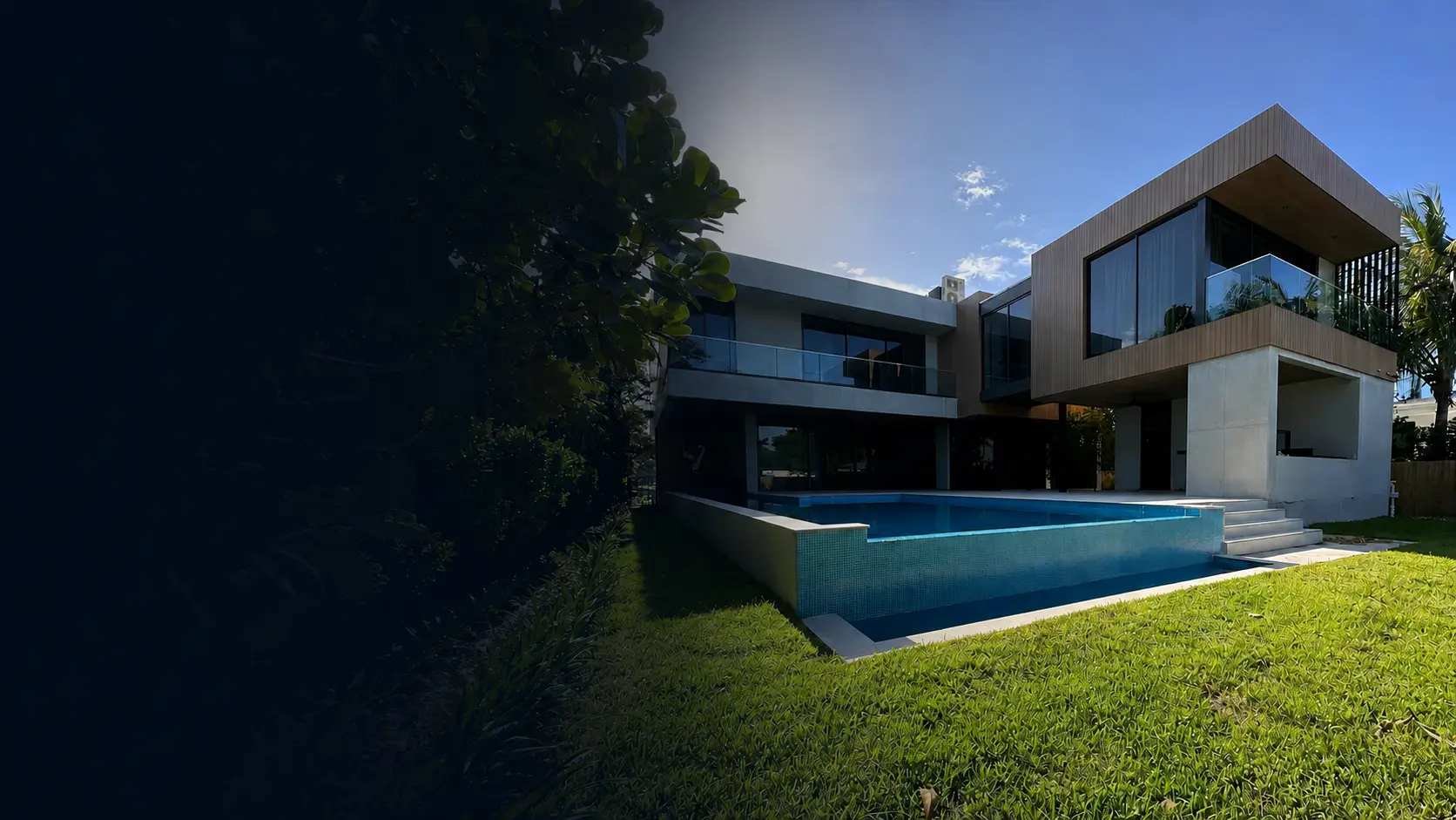 Contemporary waterfront-style residence in Miami Beach with a tiled pool, landscaped lawn, and glass-railed terraces