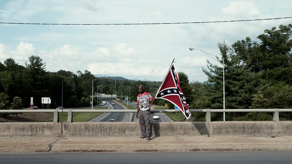 Still frame from Monumental Crossroads showing an African-American man waving a Confederate flag.