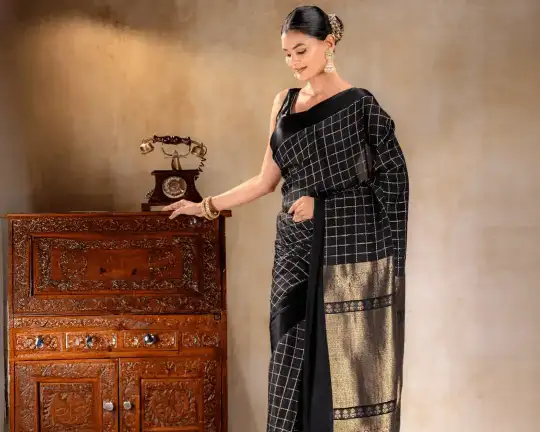 A woman wearing a black crepe saree with delicate golden borders from That Saree Shop, highlighting the saree’s fluid drape and refined craftsmanship for an elegant, modern look.