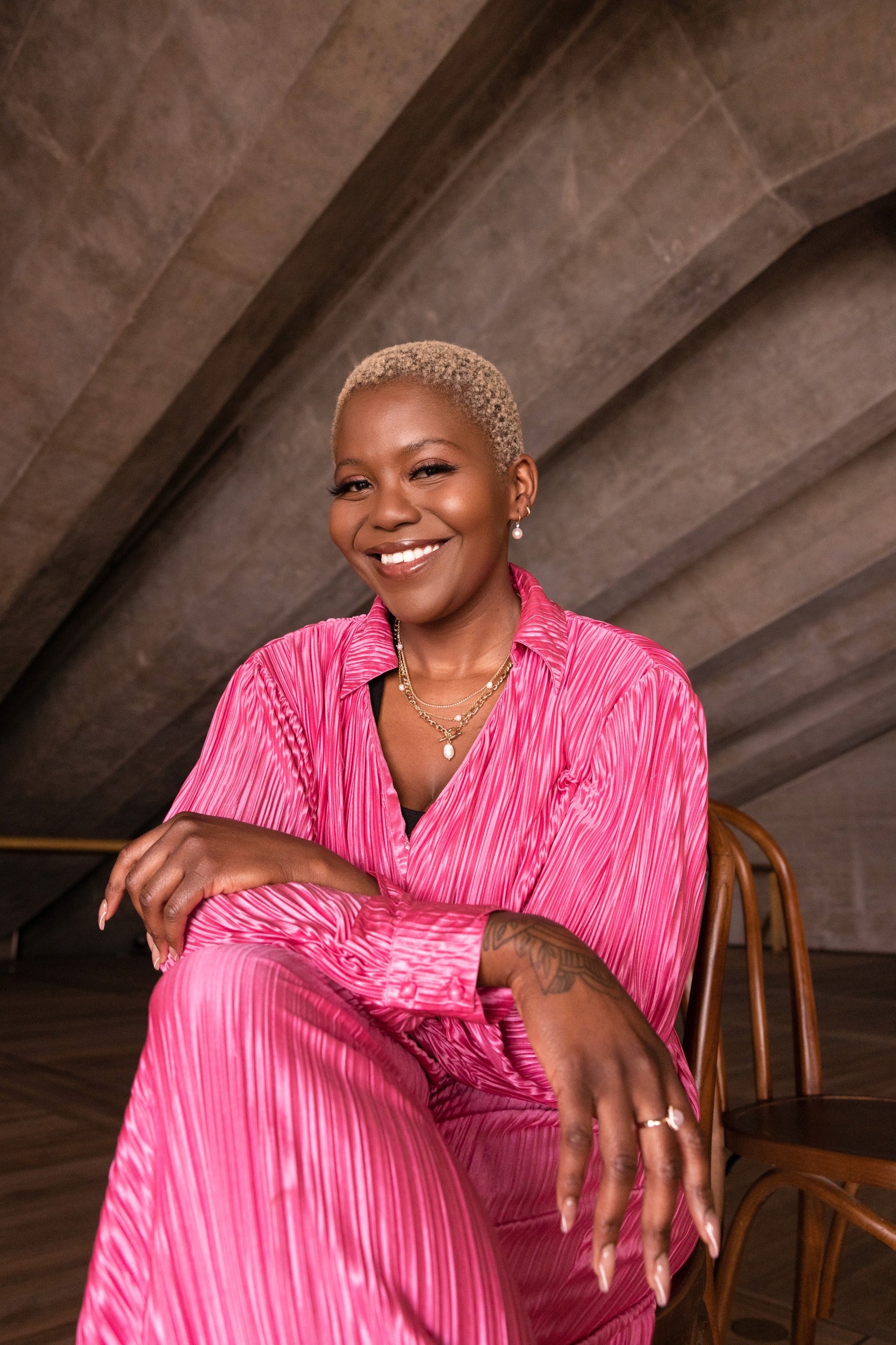 Editorial portrait in Sydney by photographer Cybele Malinowski, featuring a smiling woman with short blonde hair in a vibrant pink pleated outfit. sydney opera house actor singer