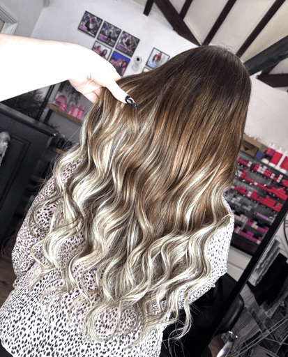 Woman with long wavy brunette hair and bleach blonde highlights in the Inspire Studio Hair Salon