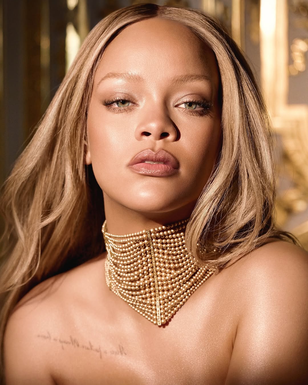 Rihanna wearing a gold pearl choker and natural glam makeup, posing for Dior J’Adore.