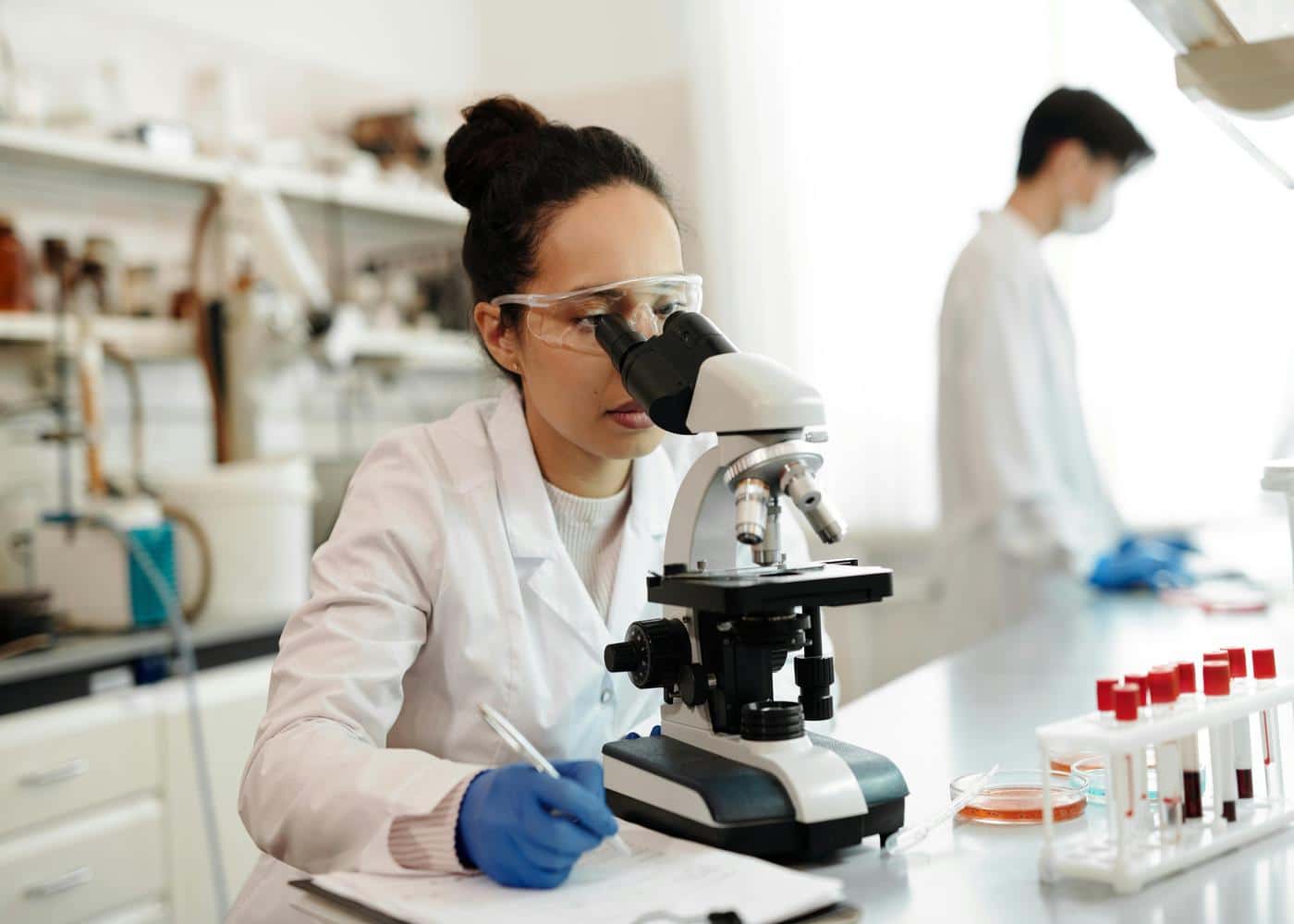 Woman in lab coat looking at miscroscope