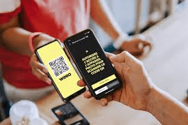 Hände halten Smartphones an der Kasse, eines zeigt einen Wero-QR-Code: die europäische Wallet, die jetzt über Nuvei verfügbar ist.