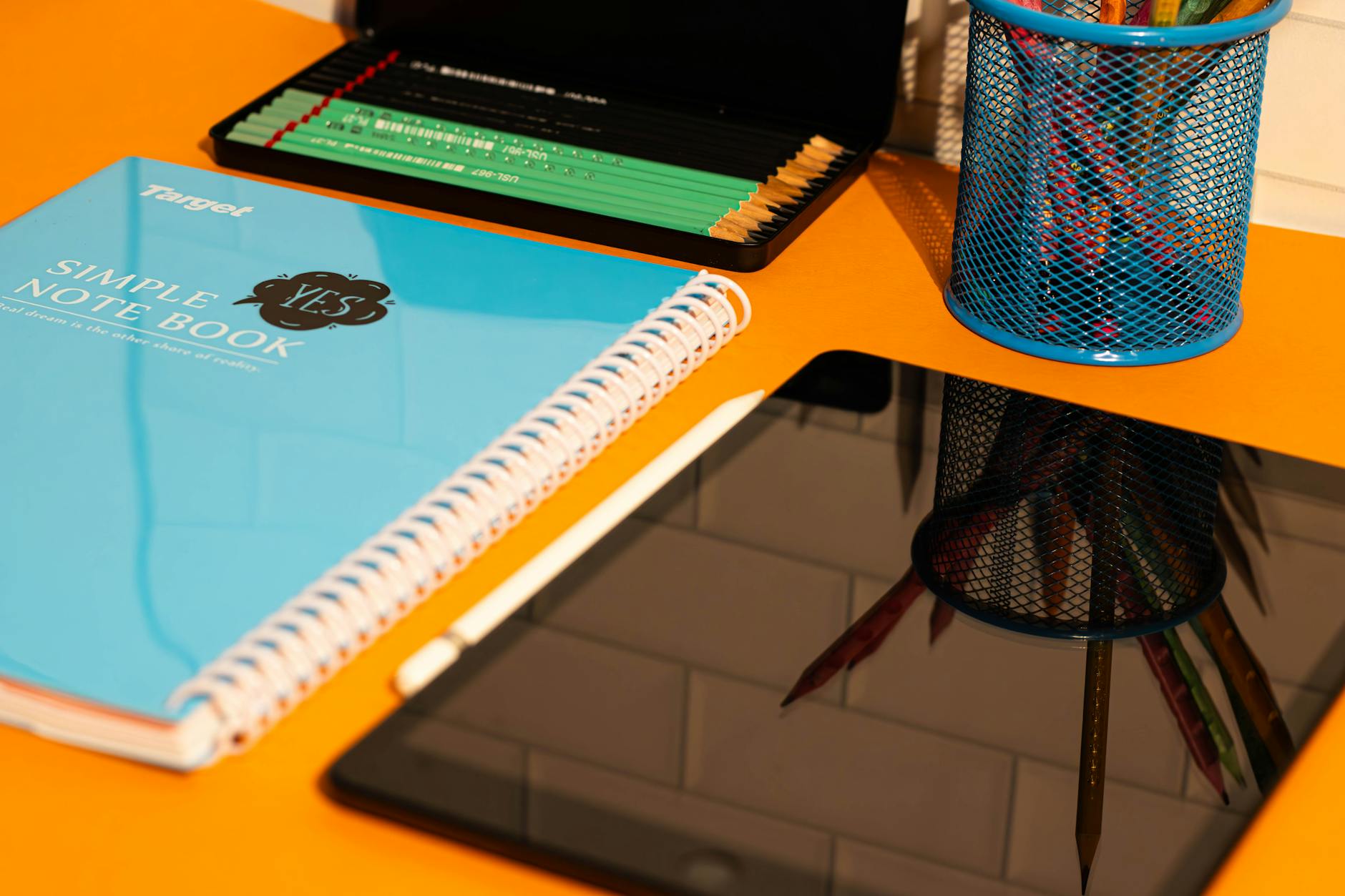 Close-up of a wooden desk featuring open textbooks, colorful markers, and a detailed lesson plan folder.