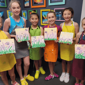 Older art class students posing with nature canvases they painted