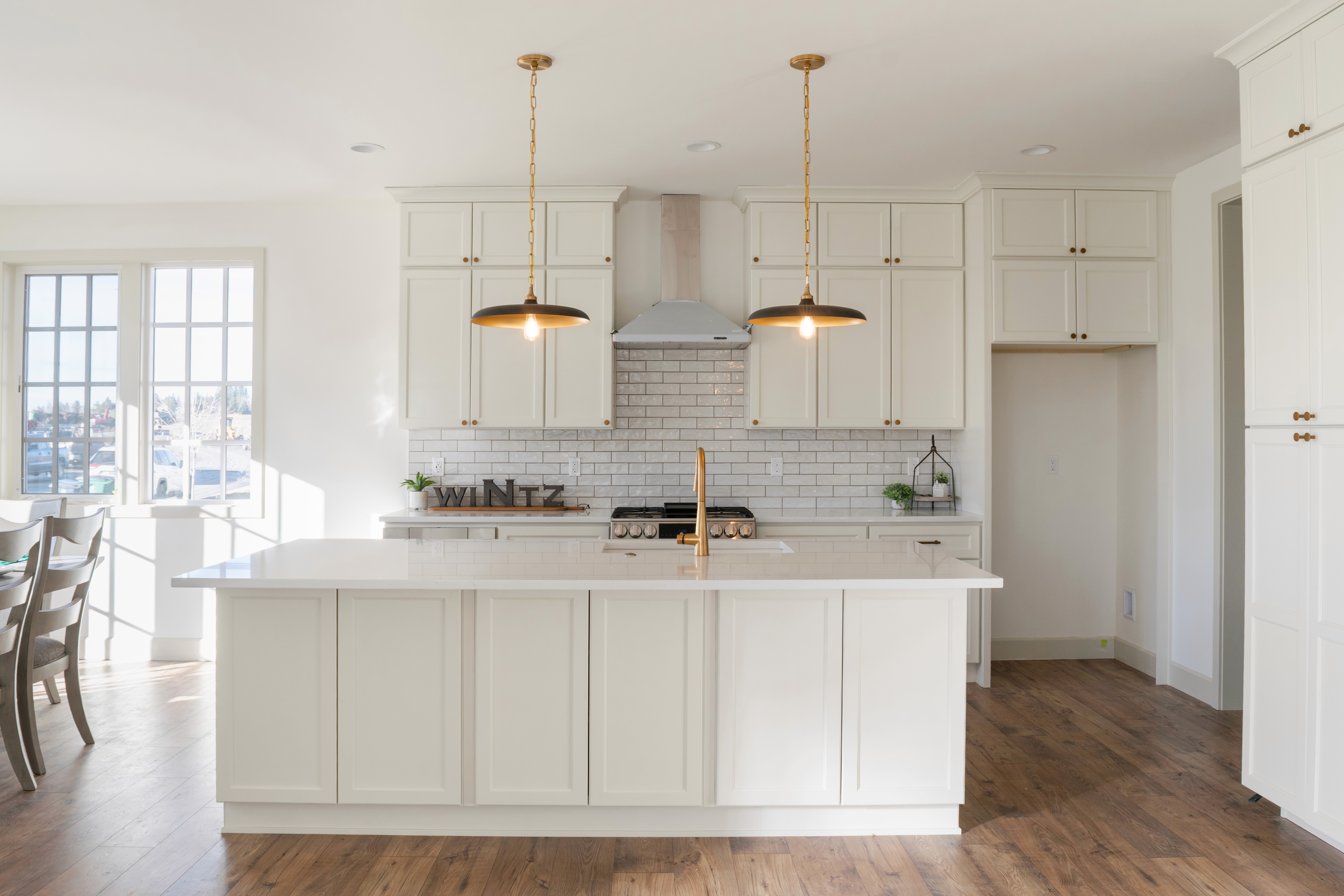 Open kitchen with large island. Dining room to the left of the kitchen and sink installed in the island. 