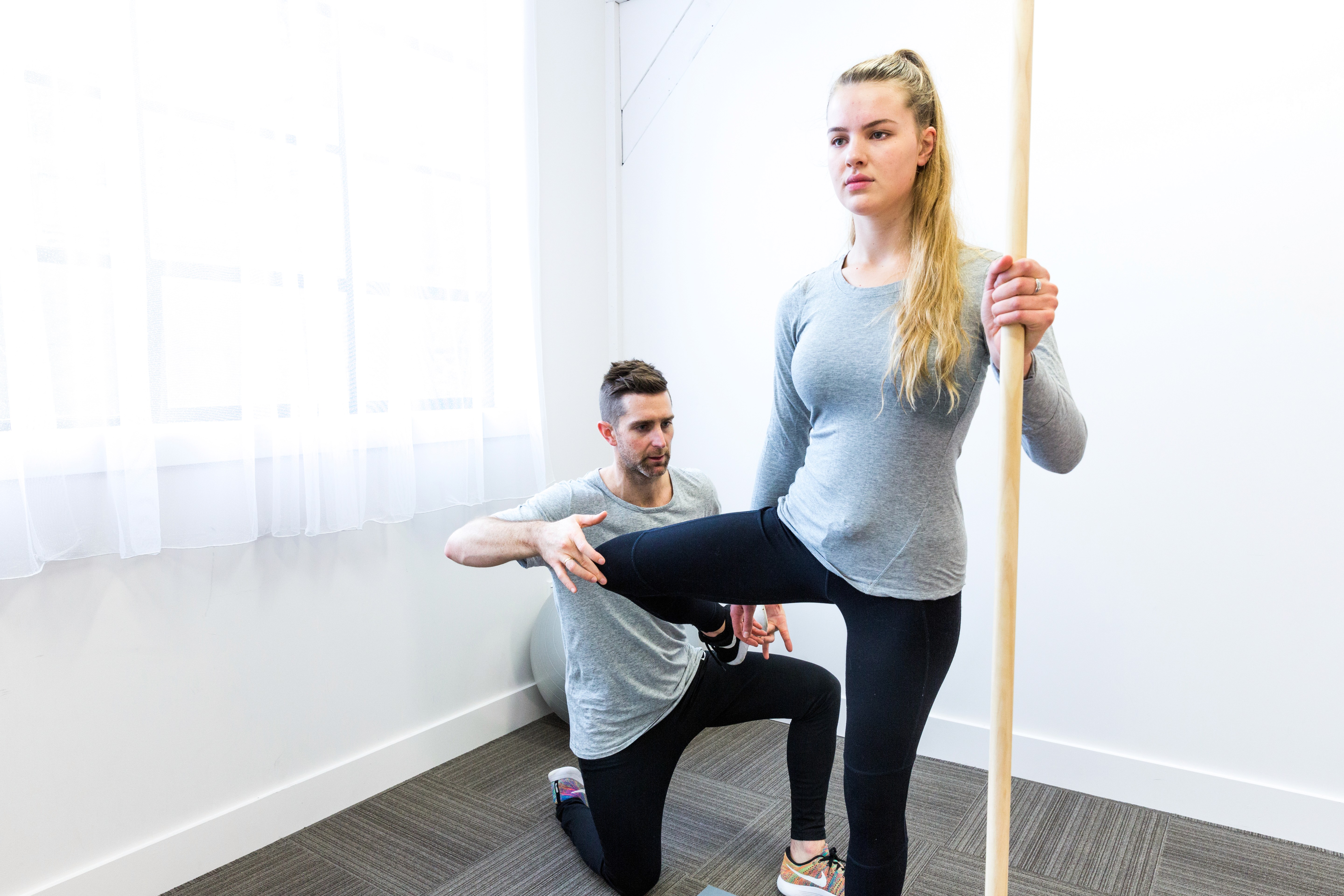 Physiotherapist assessing a client's leg balance and movement.