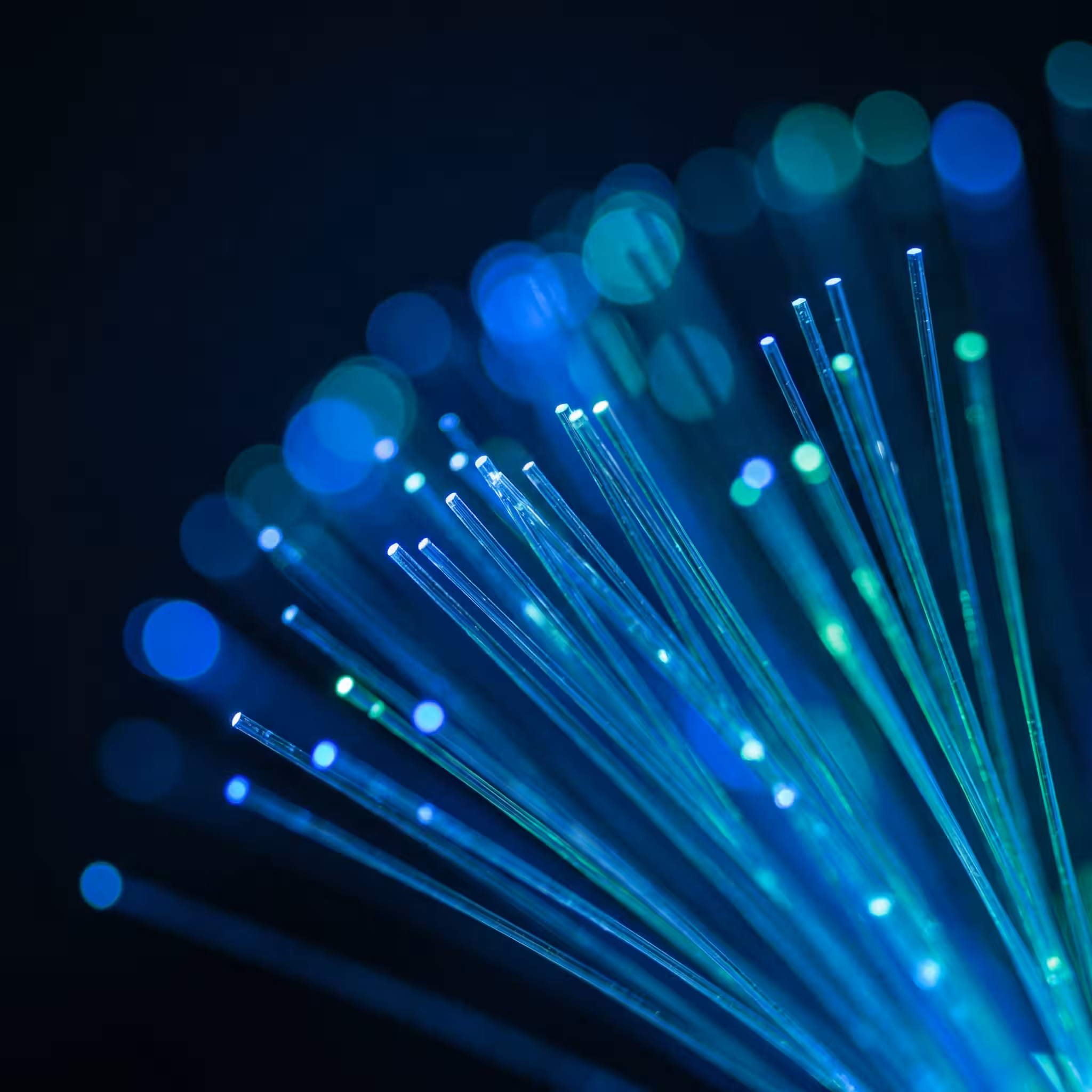 Bundle of glowing fiber optic strands fanning out against a dark background.