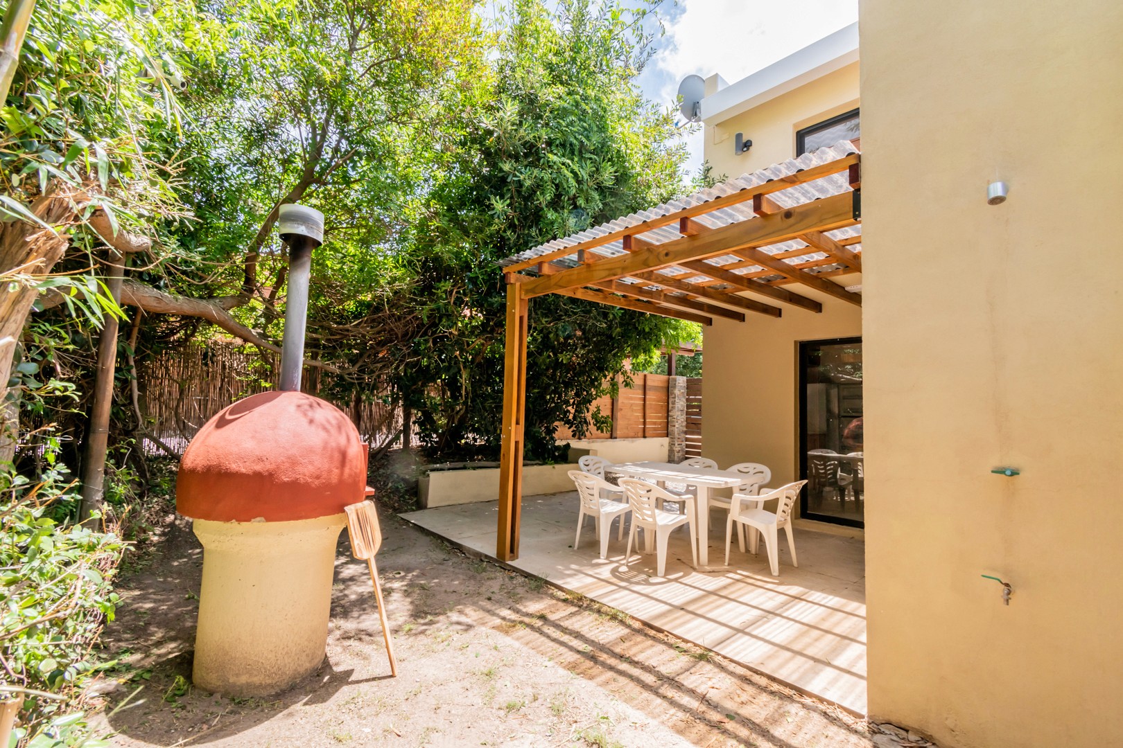 Patio trasero de Casa Albatros con parrillero y comedor exterior - zona amplia con parrillero y mesa para compartir comidas al aire libre.