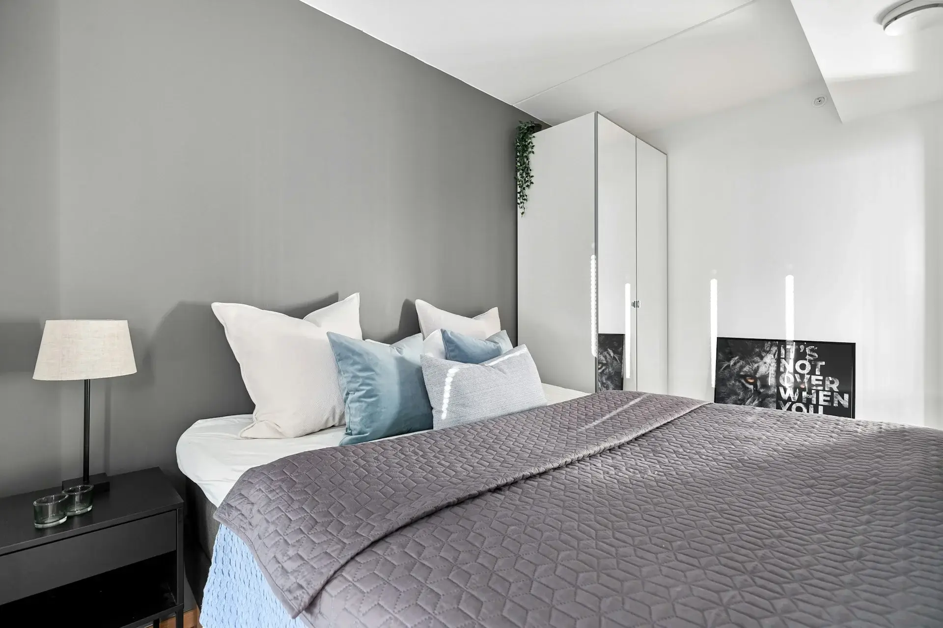 Minimal bedroom with gray walls, layered pillows, and soft lighting.
