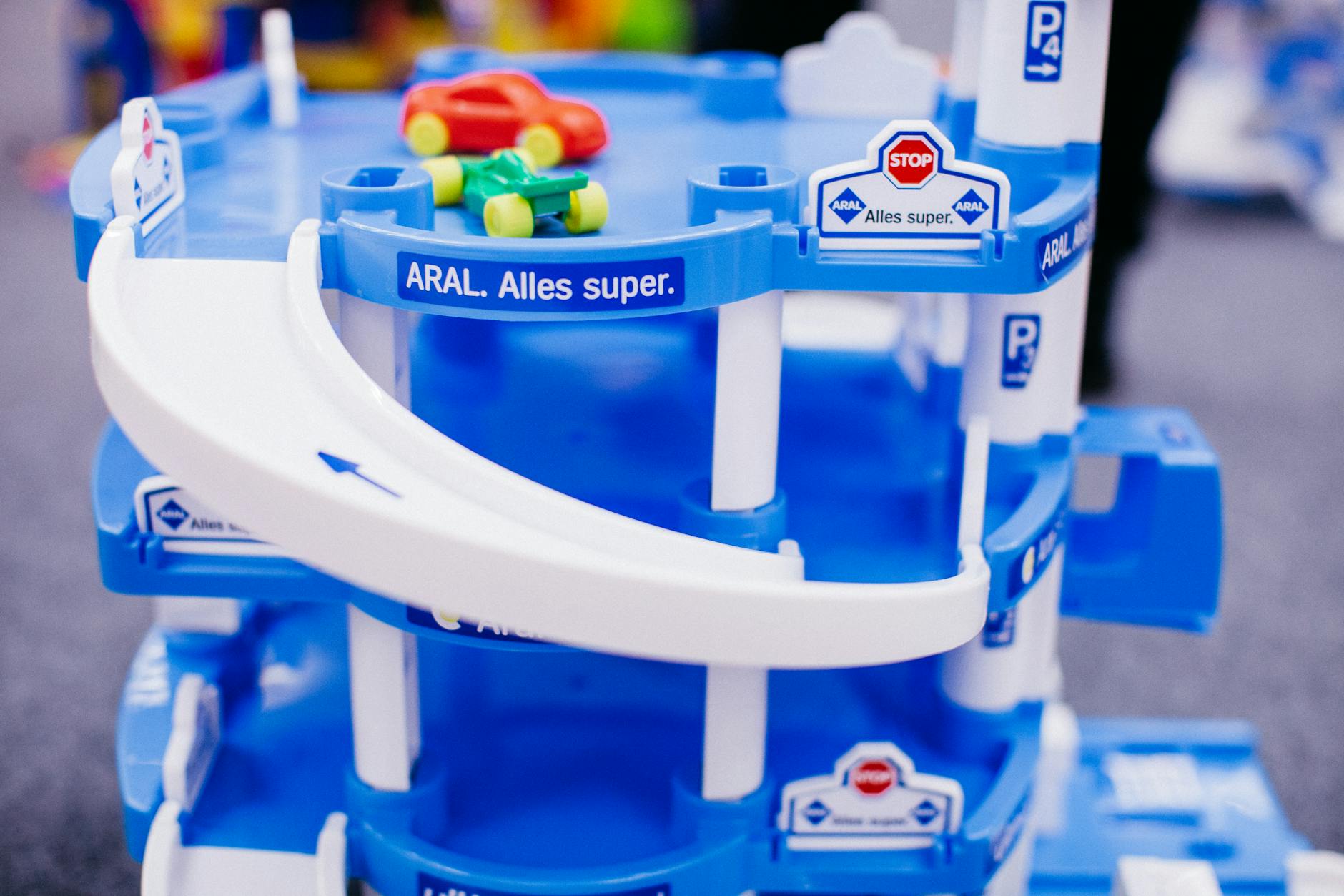 Two boys measuring the distance a wooden toy car traveled down a steep plastic ramp.