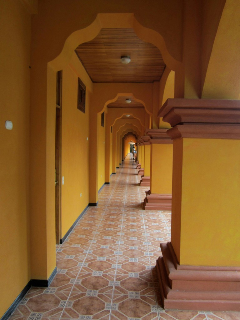 a long hallway lined with yellow walls and benches