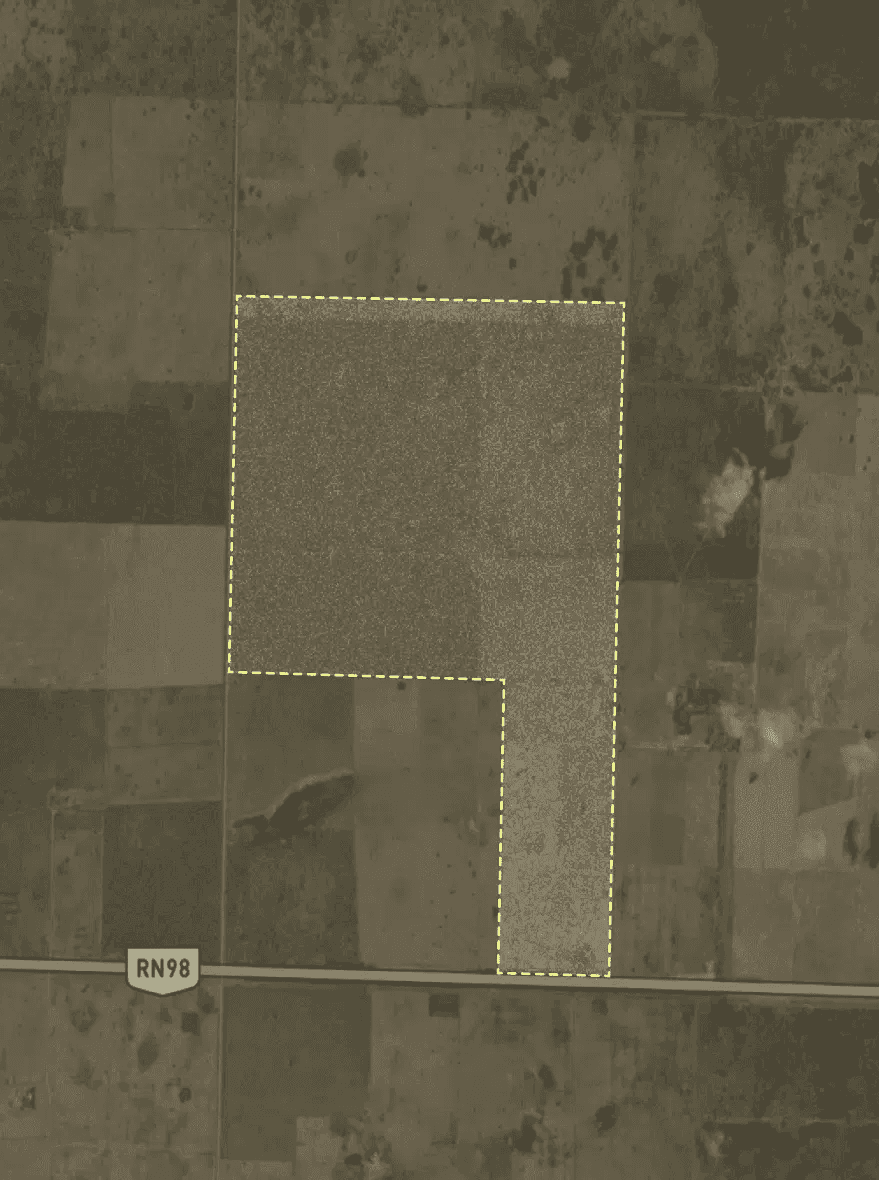 A smiling young man with crossed arms, wearing a plaid shirt and white t-shirt, poses against a dark background.
