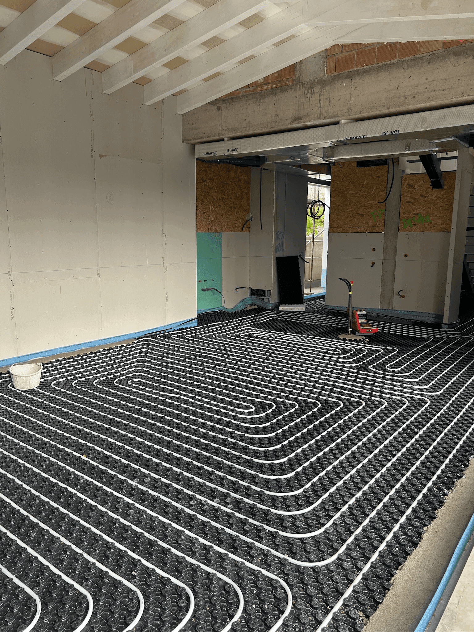 Instalación de suelo radiante por agua en una vivienda en construcción, con tuberías distribuidas sobre panel aislante antes del vertido del recrecido.