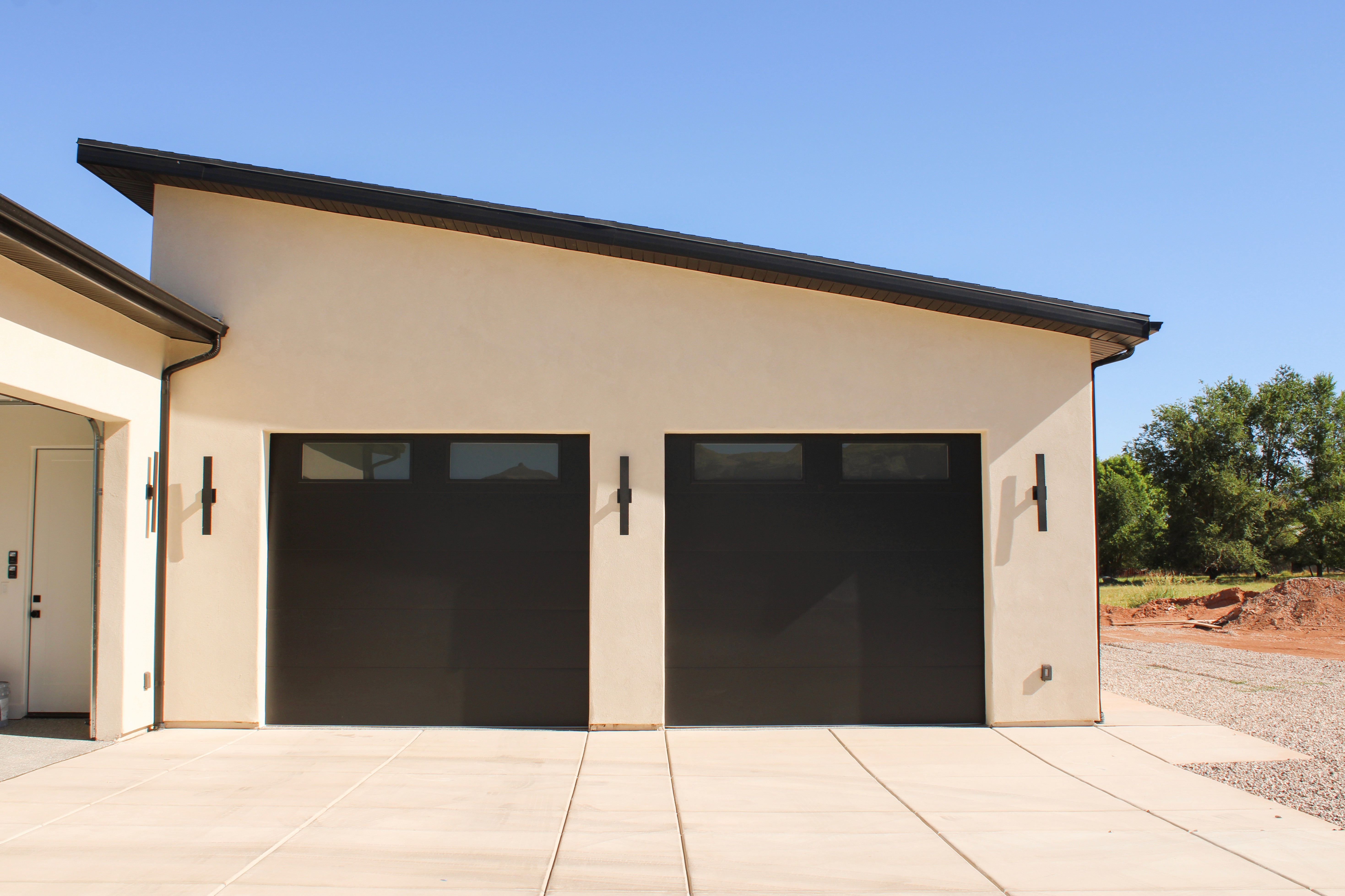Dark garage doors against light stucco bring a sophisticated and luxury feel to this home.