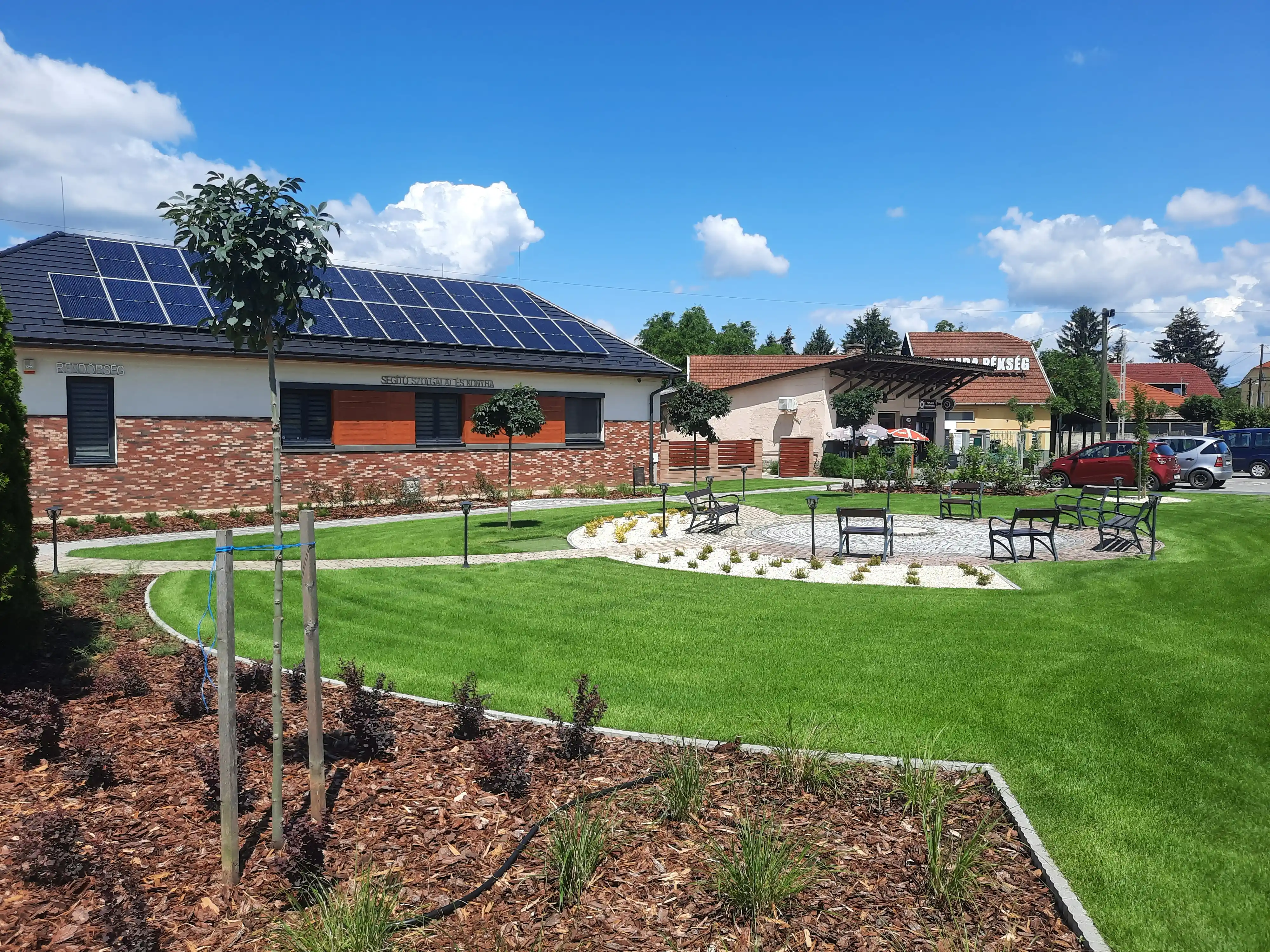 Köztéri zöldterület padokkal és újonnan telepített cserjékkel