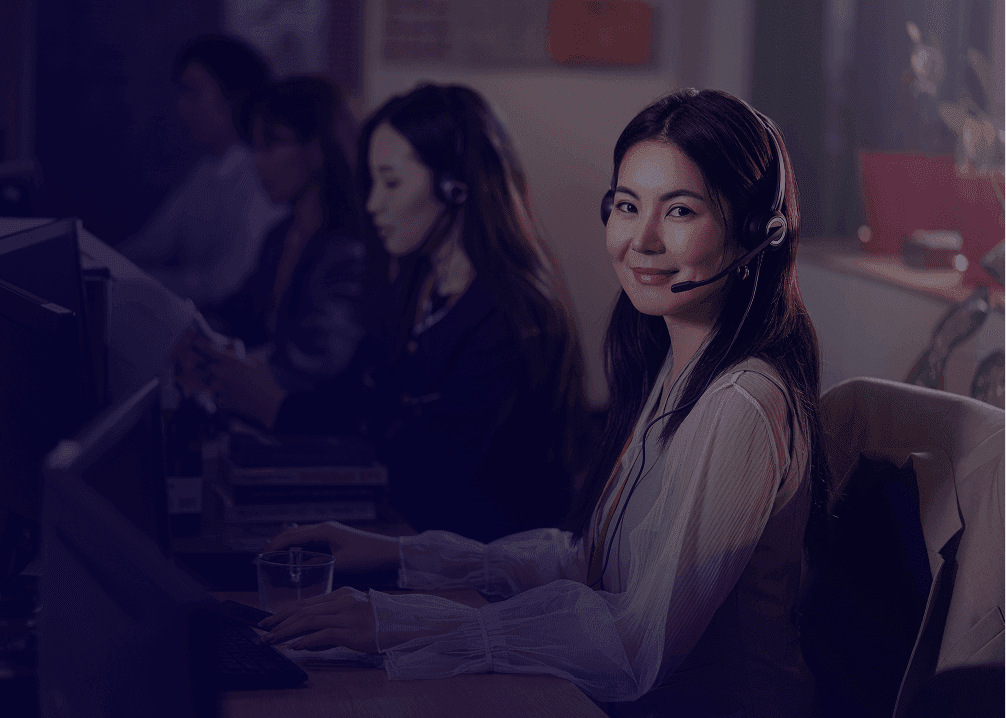 A smiling woman wearing a headset at a computer.