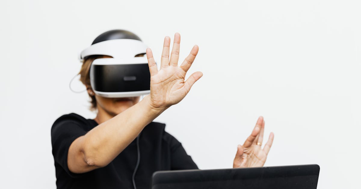 An adult wearing a VR headset interacting virtually, seated with a laptop.