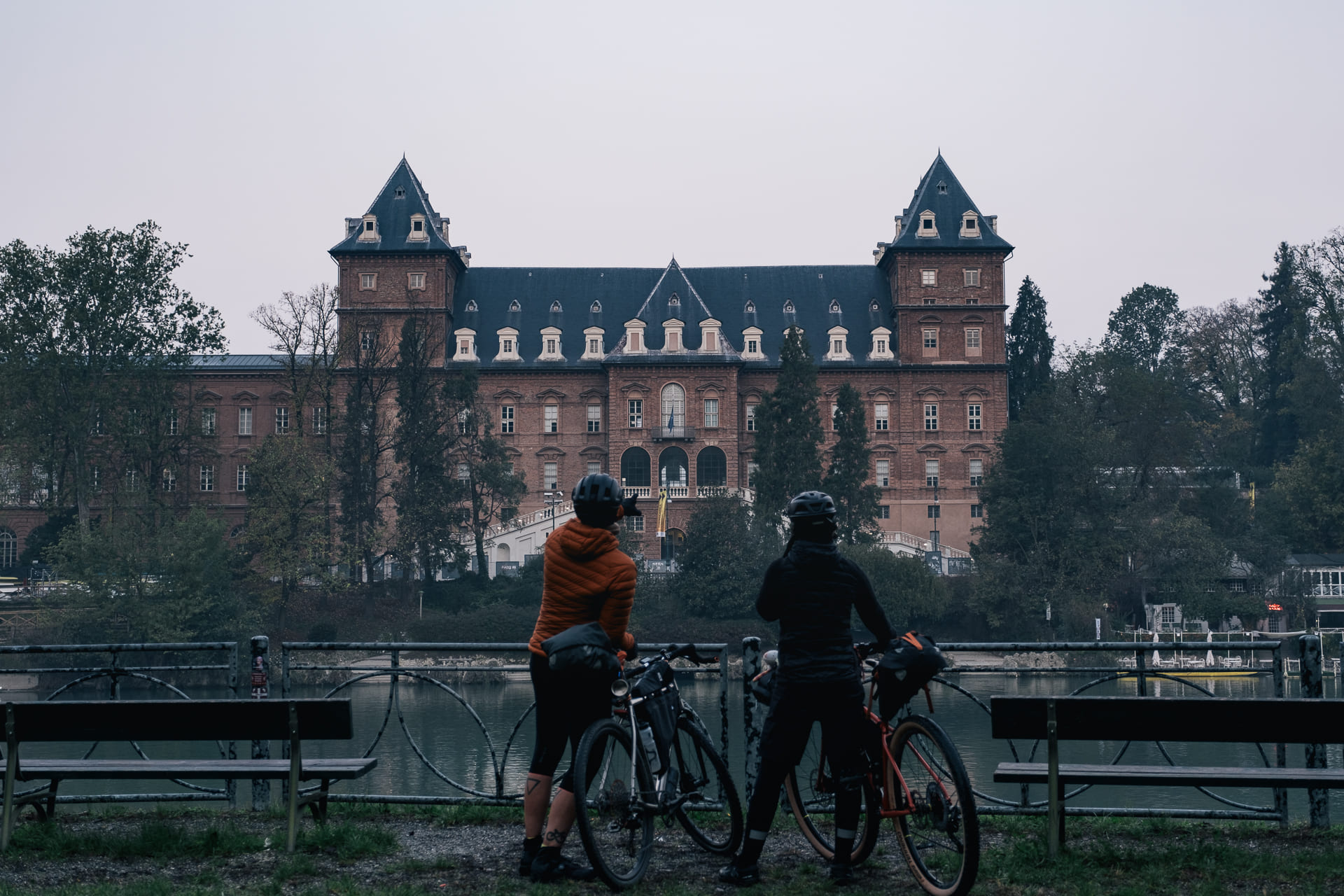 Foto con sfondo il castello del valentino e due ciclisti che lo contemplano