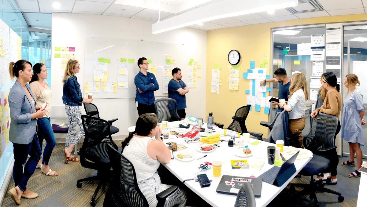 A group of colleagues listening to a workshop facilitator explaining an exercise
