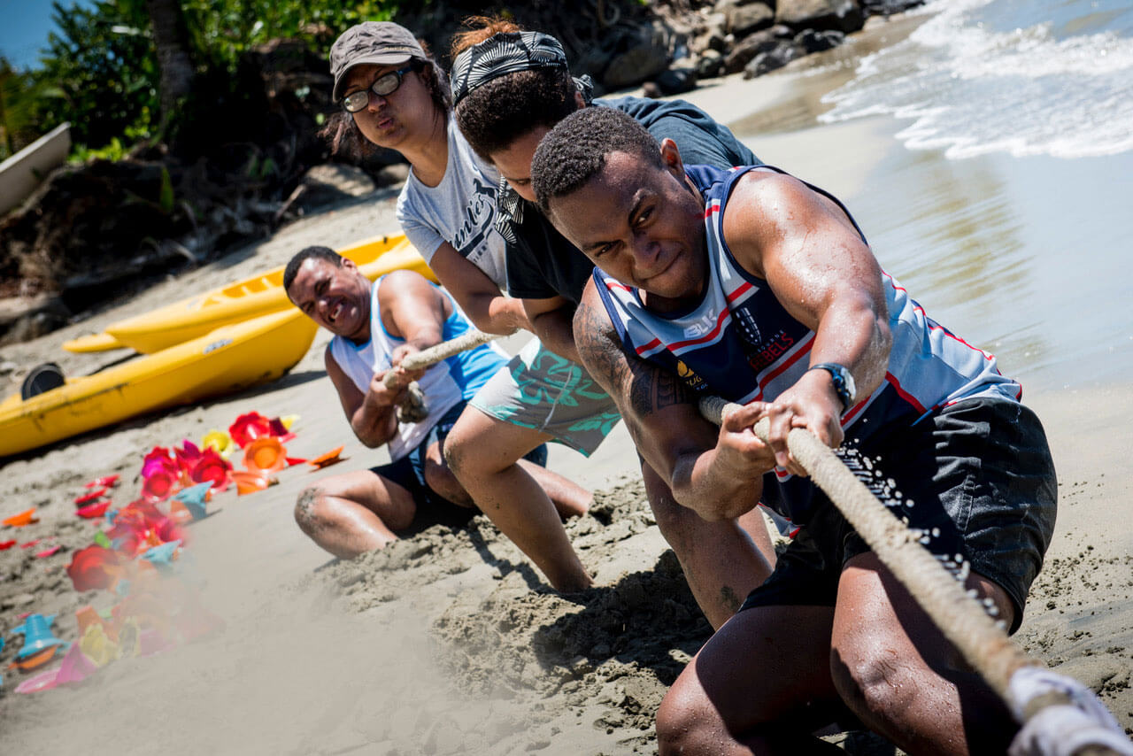 group team building activity on the beach with people playing tug of war in Fiji
