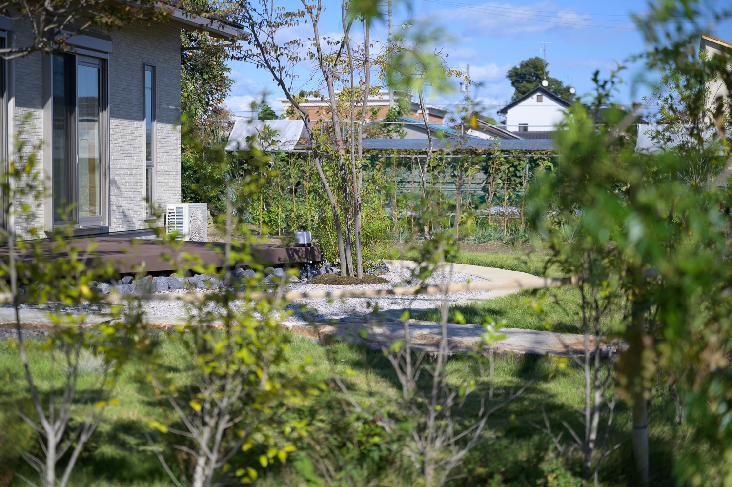 玄関とウッドデッキを囲むようなアプローチが特徴的だ。