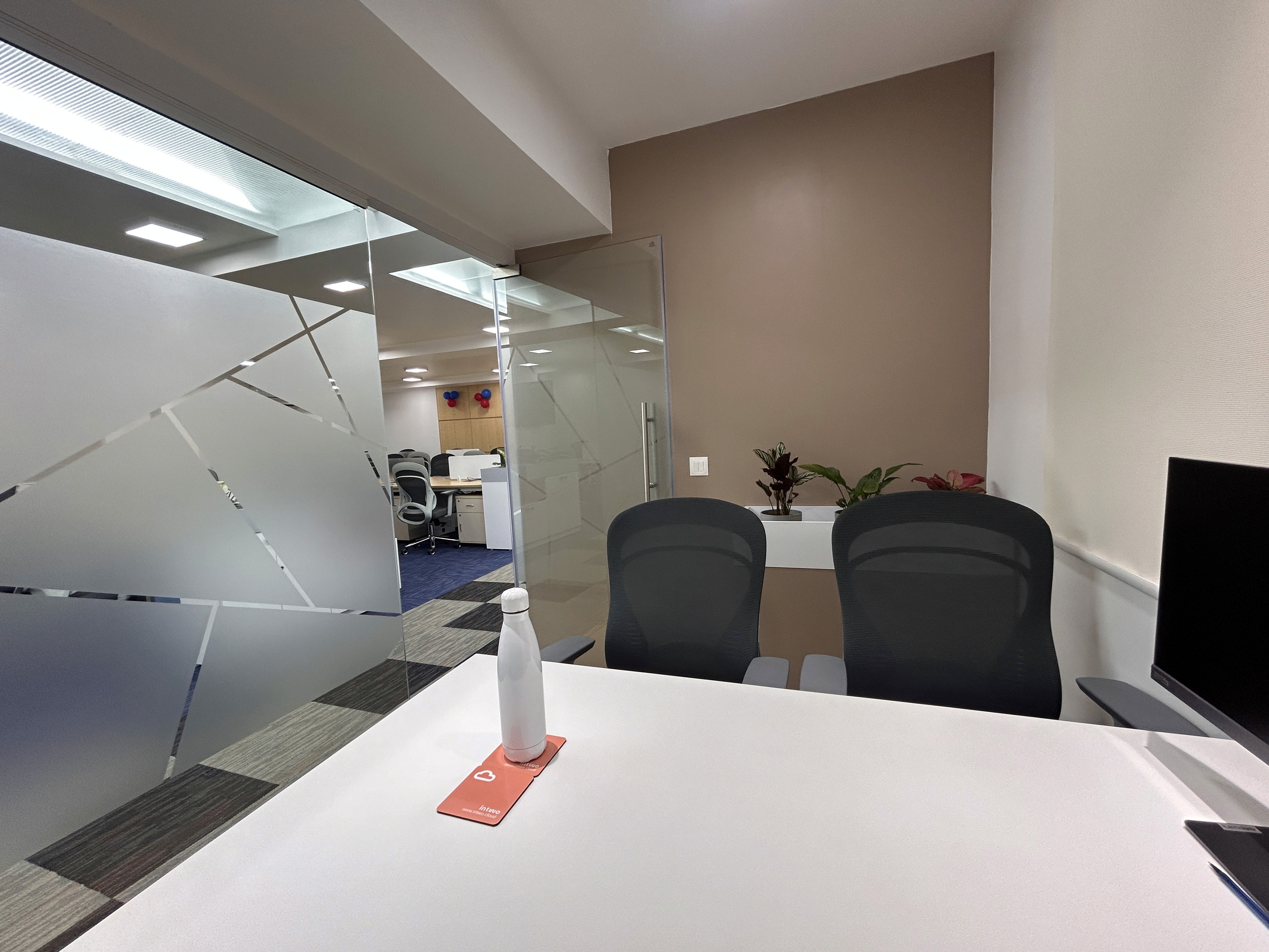 Modern office interior with glass walls, desk, chairs and water bottle.  