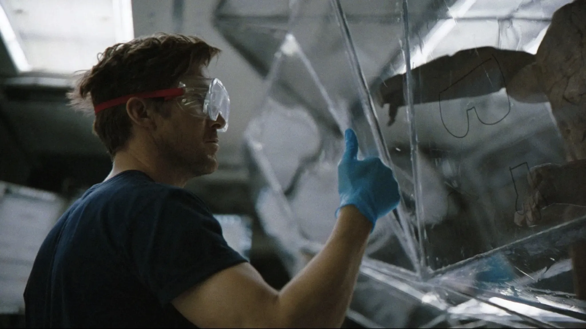 Ryan Gosling as Ryland Grace in the Hail Mary spacecraft, with Rocky the alien, from the Project Hail Mary movie trailer wearing protective goggles and gloves, highlighting concepts of space travel and scientific research.