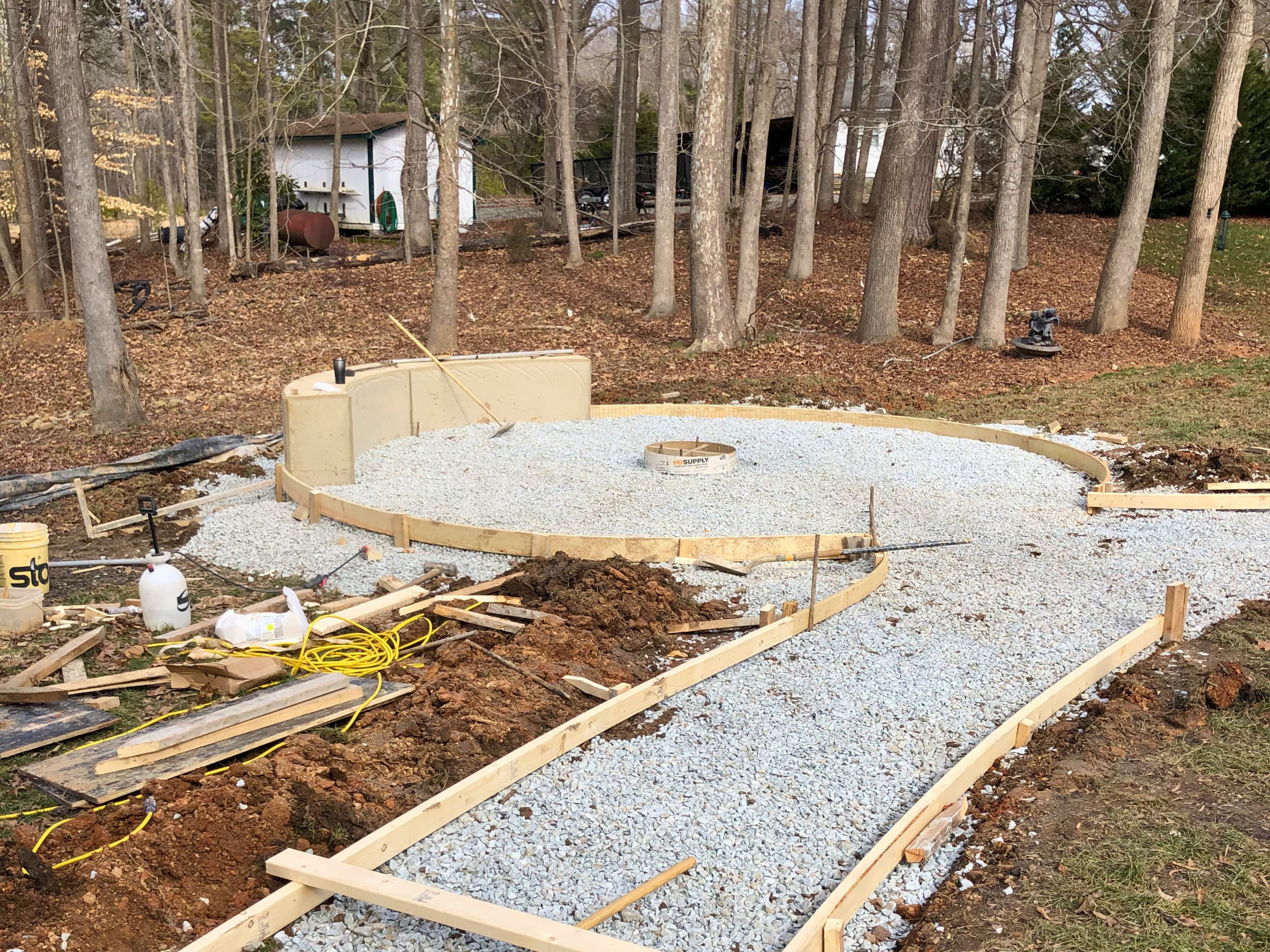 In‑progress view of the round concrete fire pit pad and curved walkway before landscaping is installed at a residential home in Durham, North Carolina.