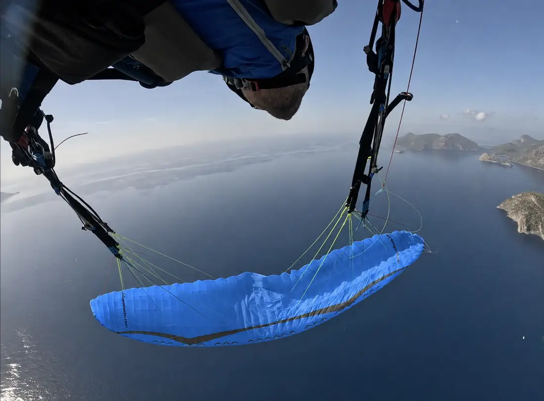 Blue paraglider flying over open water