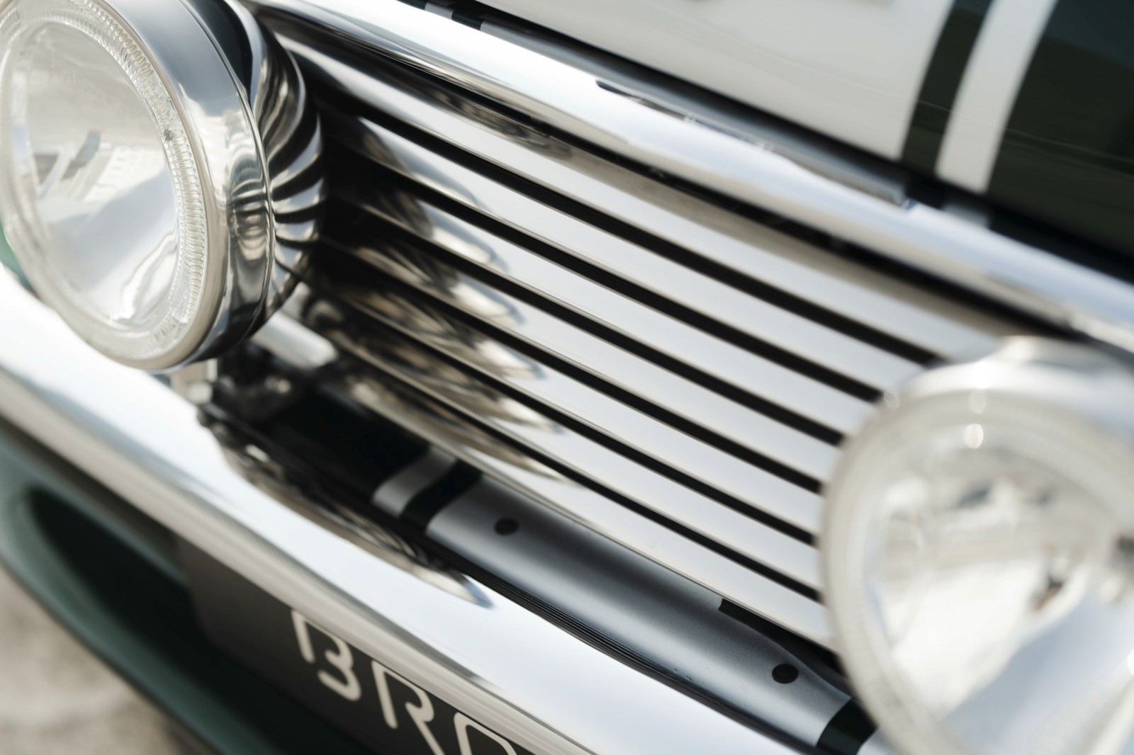 Close-up of a car's front grille with polished chrome bars and headlights, showcasing a classic design.