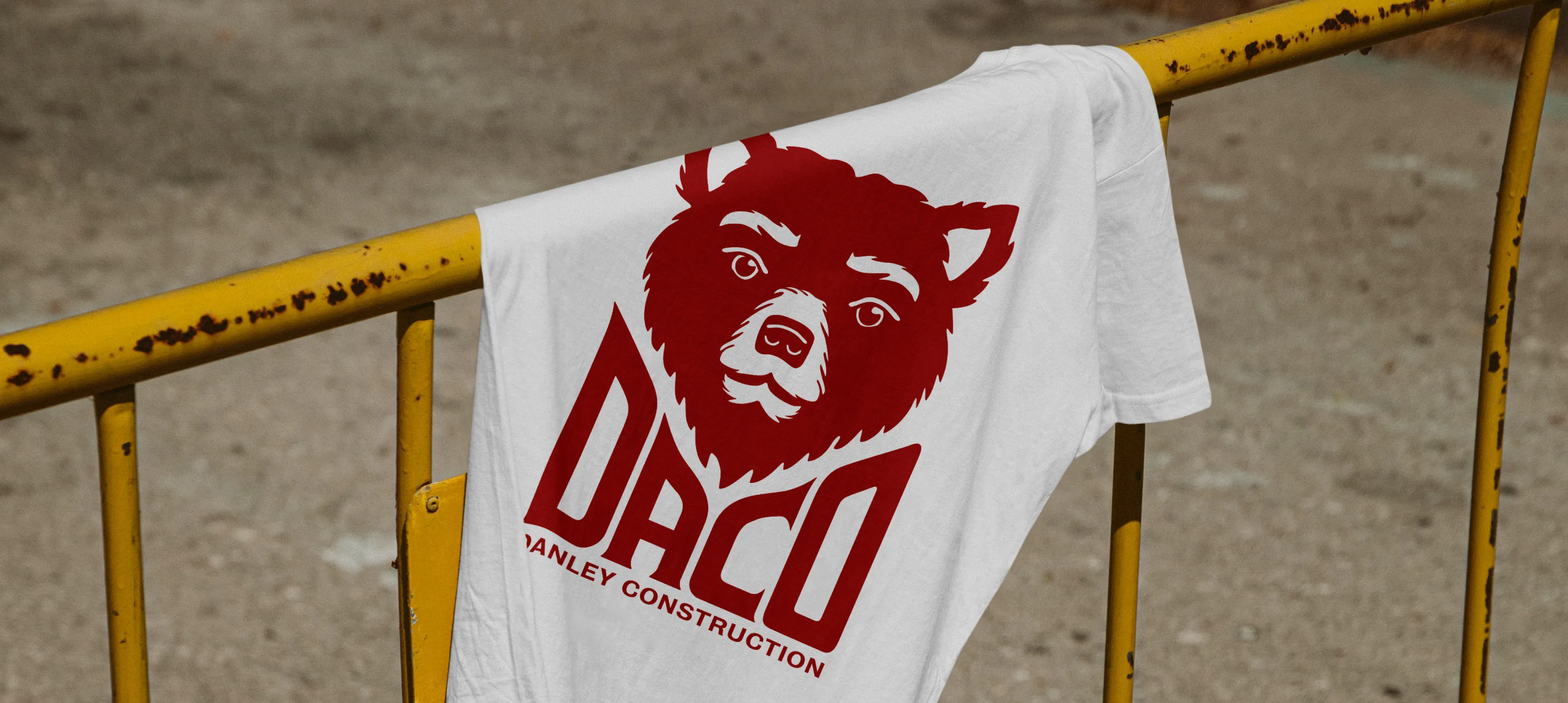 A DACO bear shirt hanging on a yellow construction fence. 