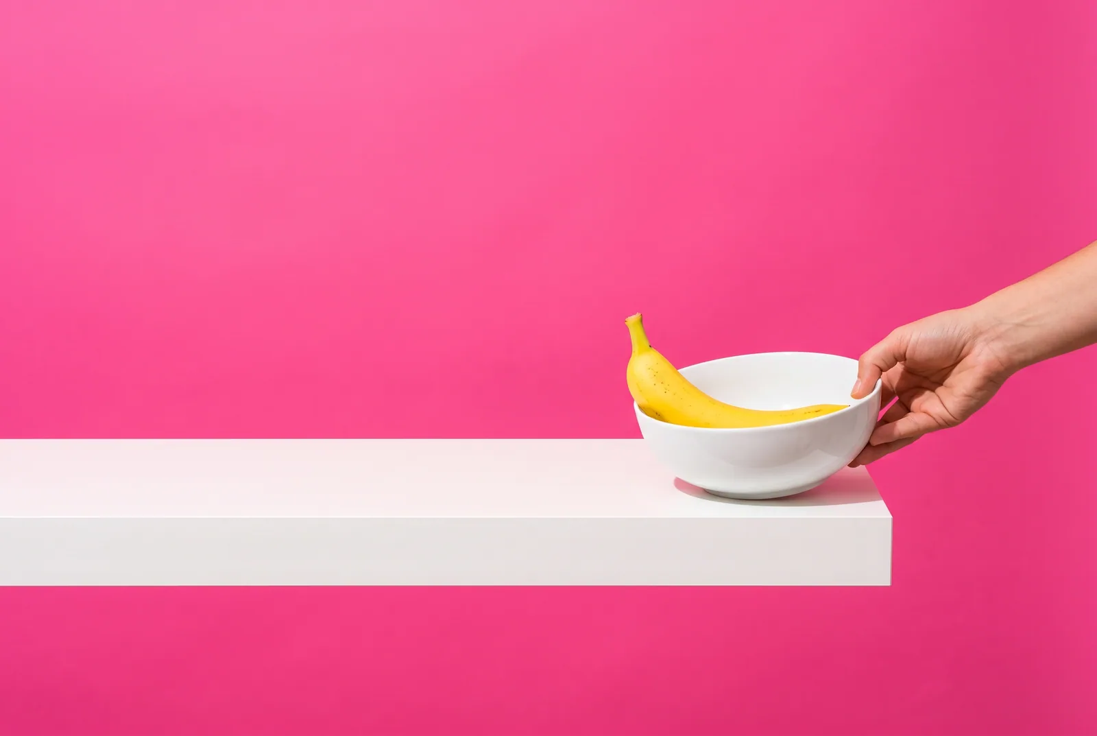 A hand sliding a bowl with a banana to the far end of a shelf, changing your environment in a porn relapse prevention plan