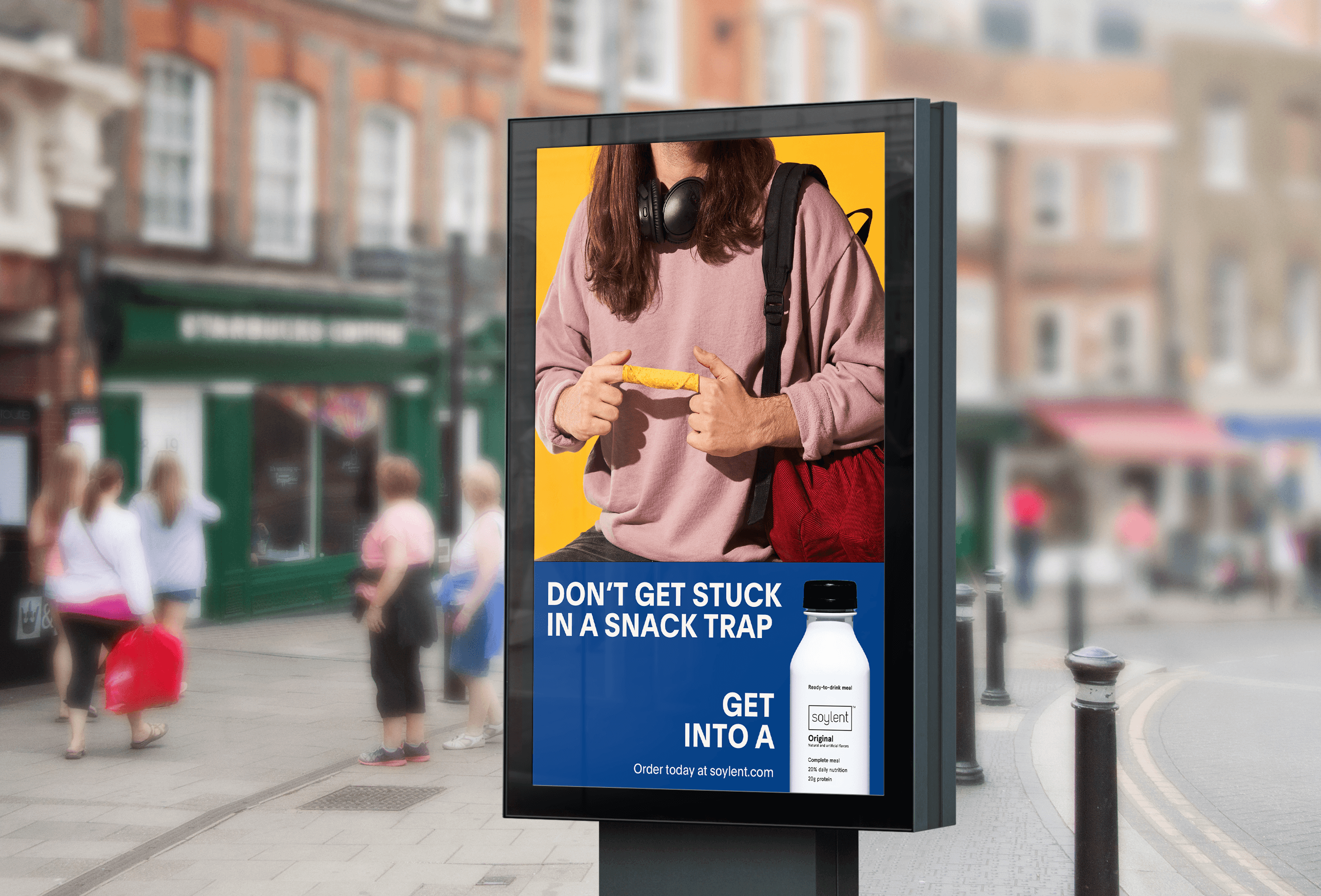 A street ad shows a man with his fingers stuck in a taquito, with a suggestion to have Soylent instead