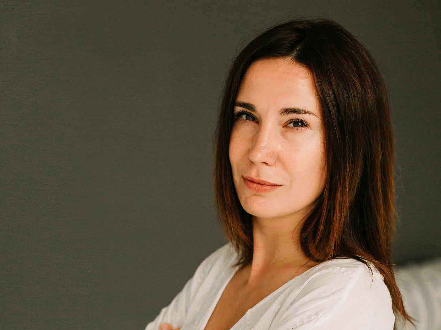 Портрет жінки-репетитора німецької мови у білій блузі на нейтральному фоні