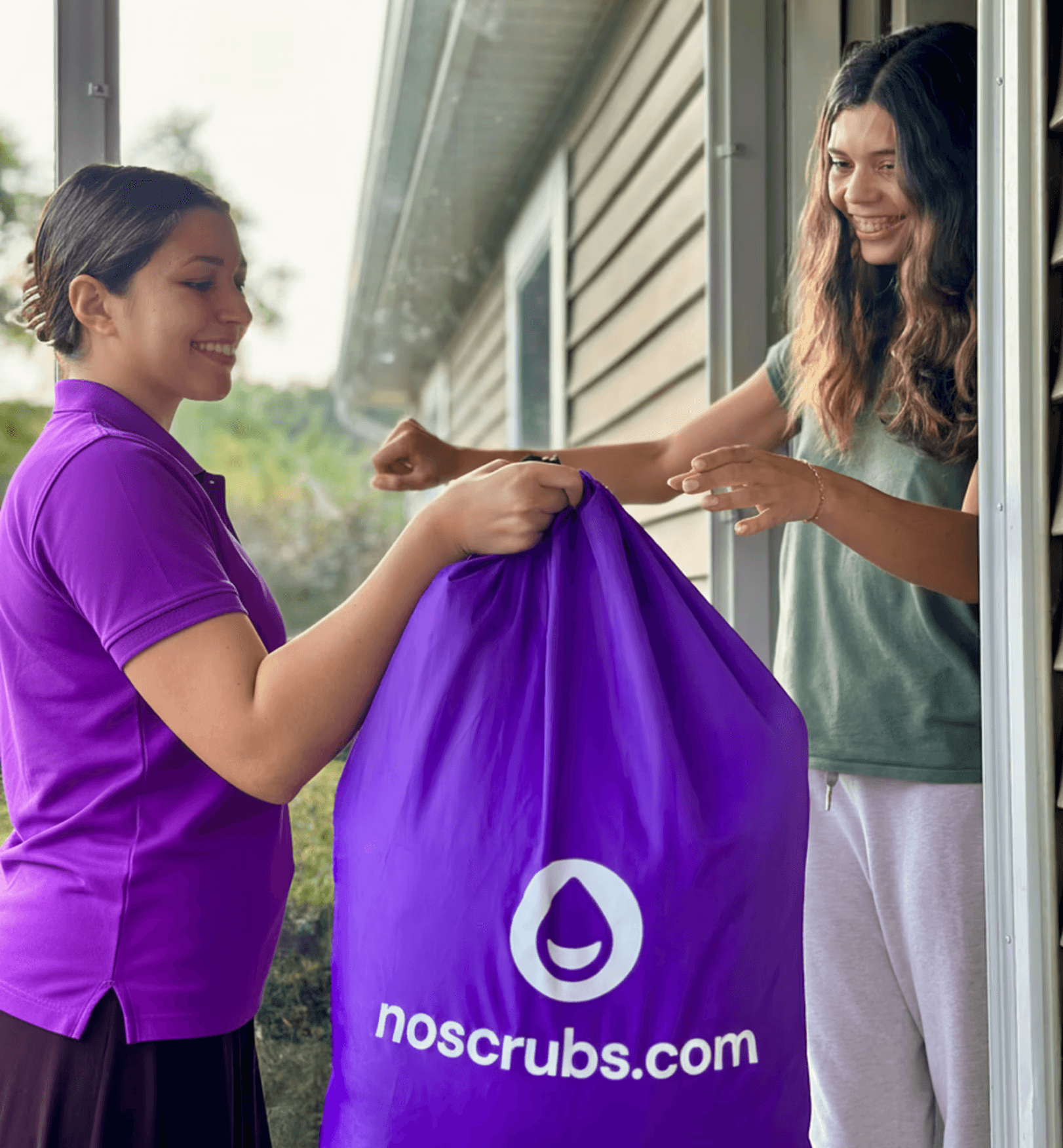 A NoScrubs Scrubber handing a laundry bag of clean clothes to a customer at her doorstep.
