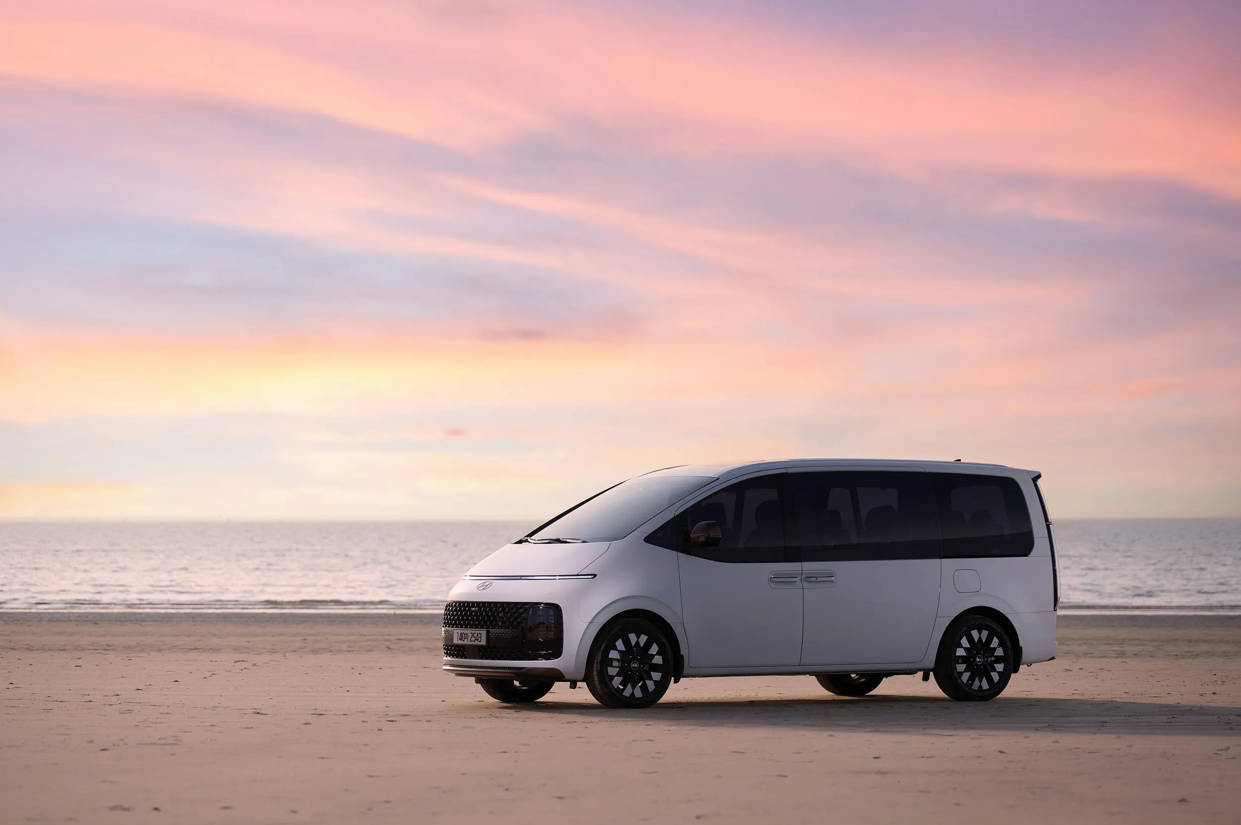 Electric van parked on sandy beach at sunset, eco-friendly family transportation